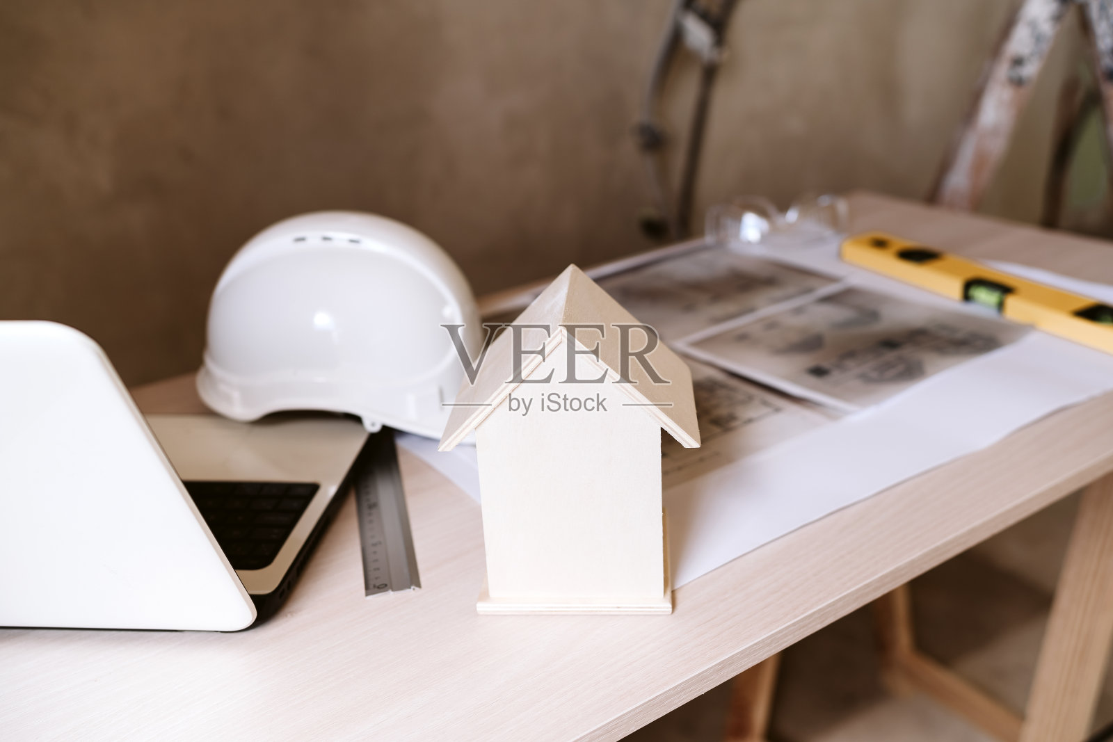 蓝图，防护头盔，笔记本电脑，房子模型和工具在建筑师的工作空间。建筑工地照片摄影图片