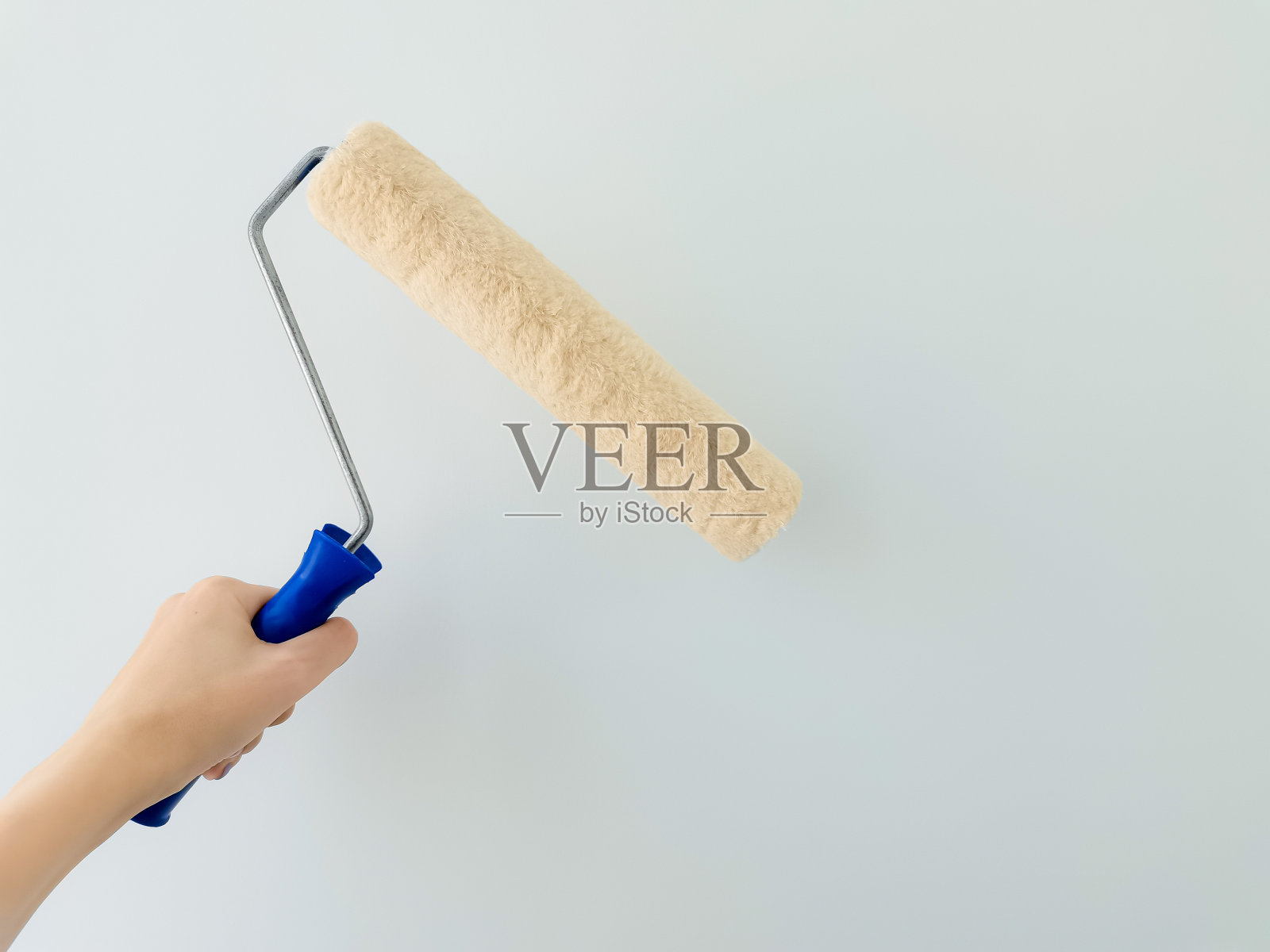 女孩用白漆漆墙。女性手与墙漆辊关闭与复制空间照片摄影图片