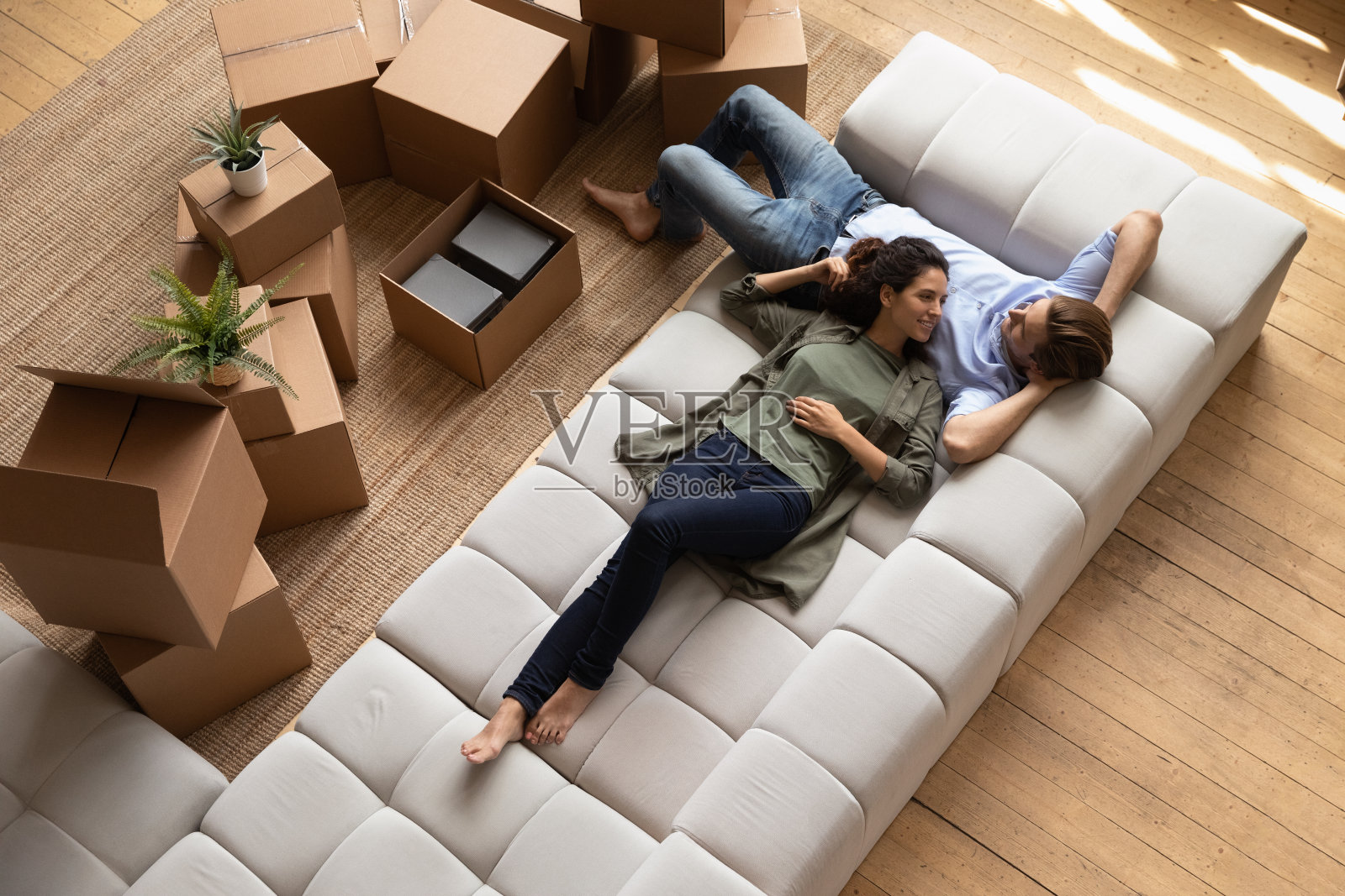 俯瞰的一对夫妇在沙发上放松，靠近纸箱照片摄影图片