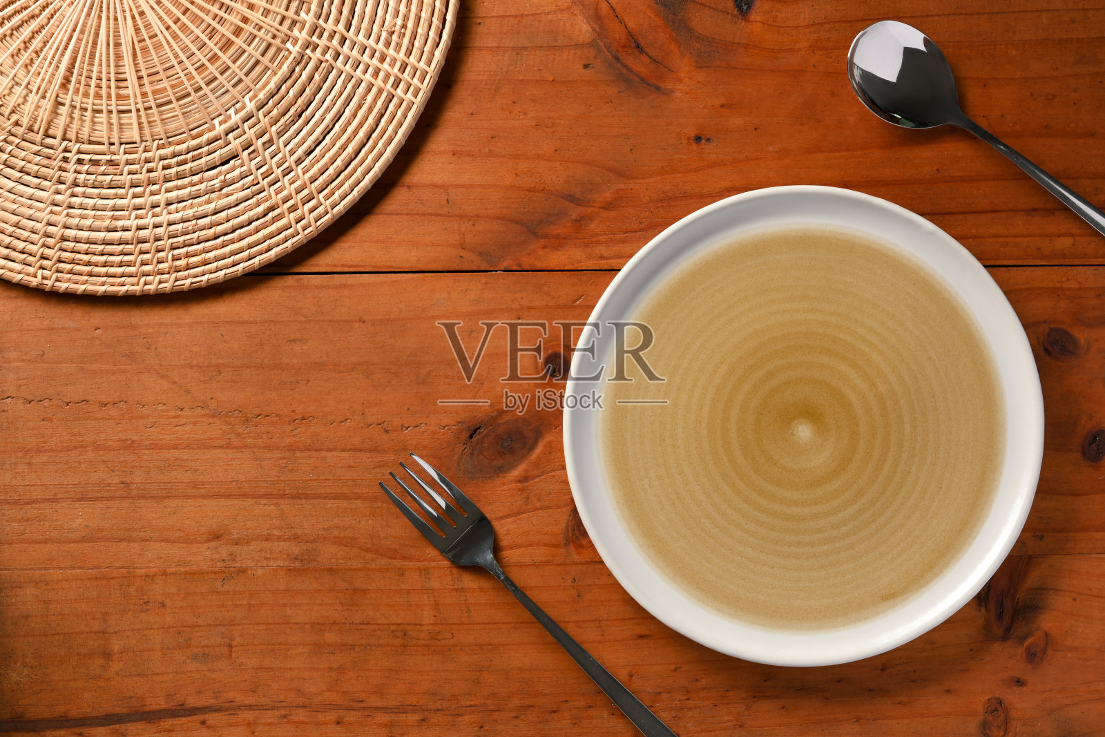 空白盘子，勺子，叉子，竹制餐垫在木制餐桌上照片摄影图片
