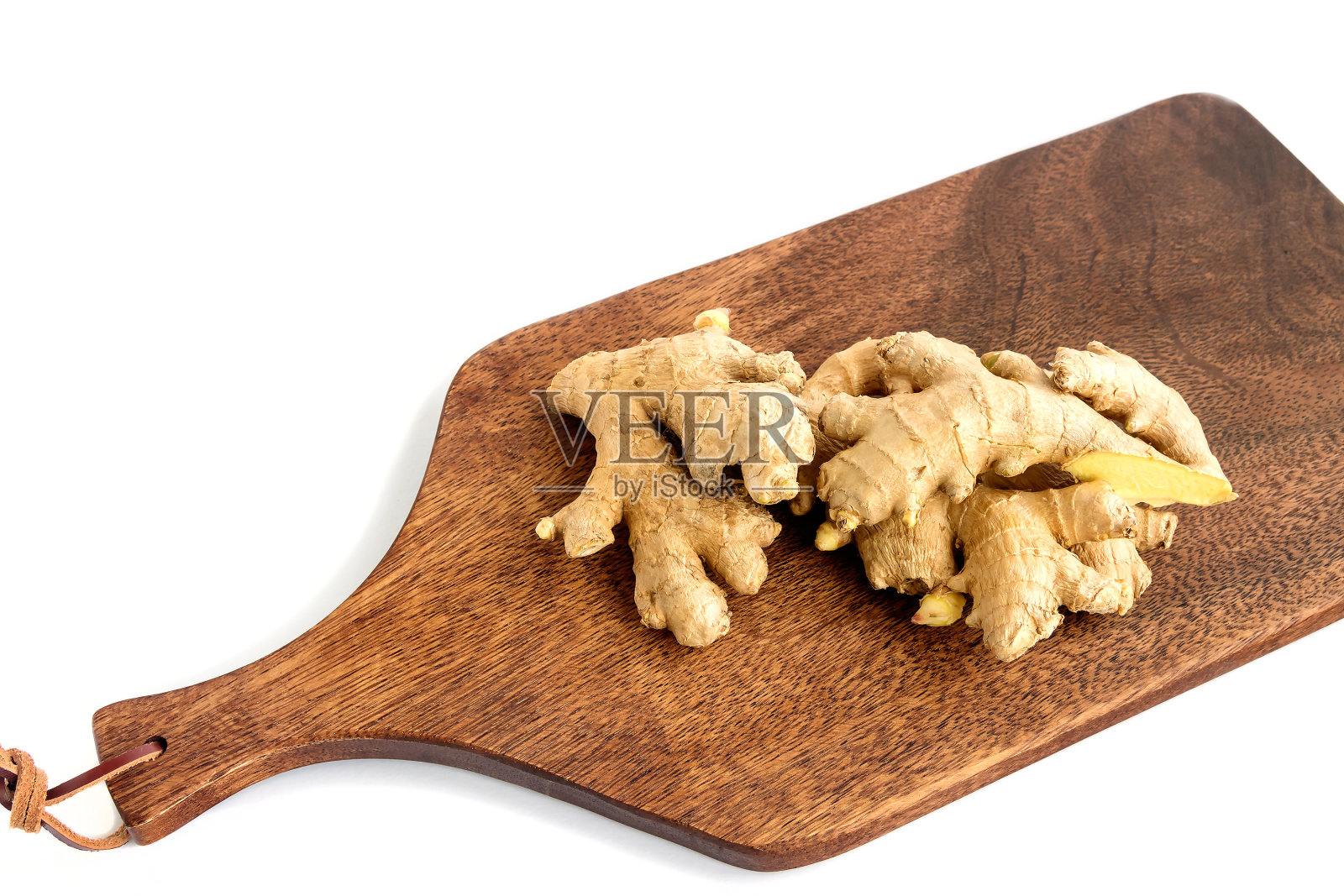 新鲜的生姜根躺在厨房的深色木板上，白色的孤立背景。照片摄影图片