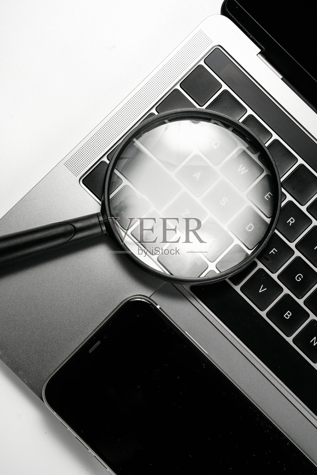 电脑，手机和放大镜在白色背景板上照片摄影图片