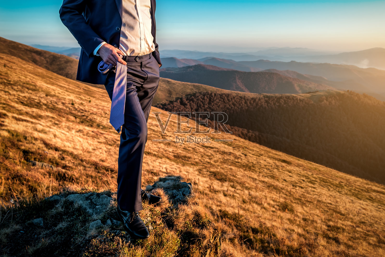 在山里，一个商人手里拿着一条领带照片摄影图片