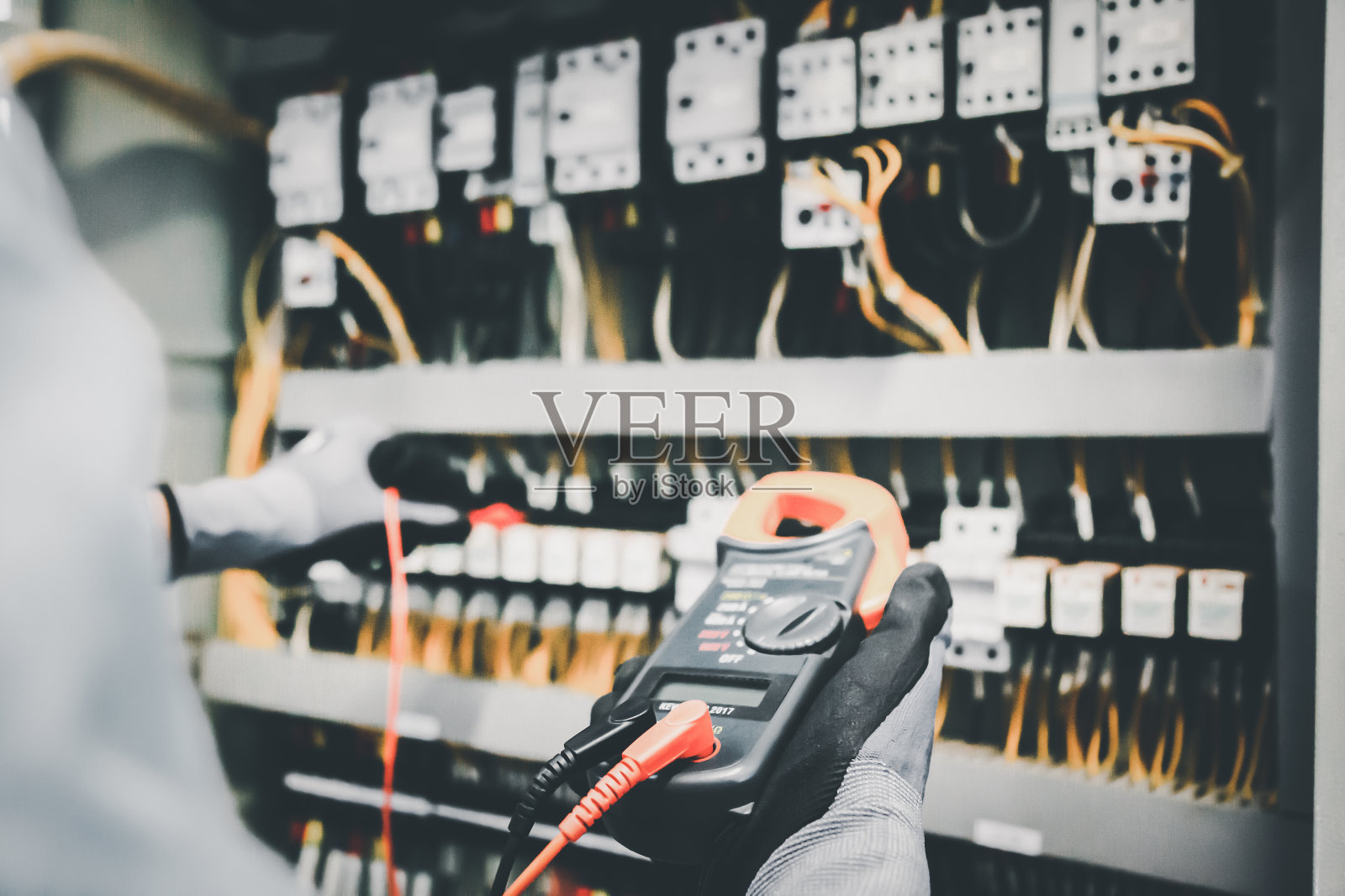 电气工程师用万用表测试电气安装和保护继电器接线。照片摄影图片