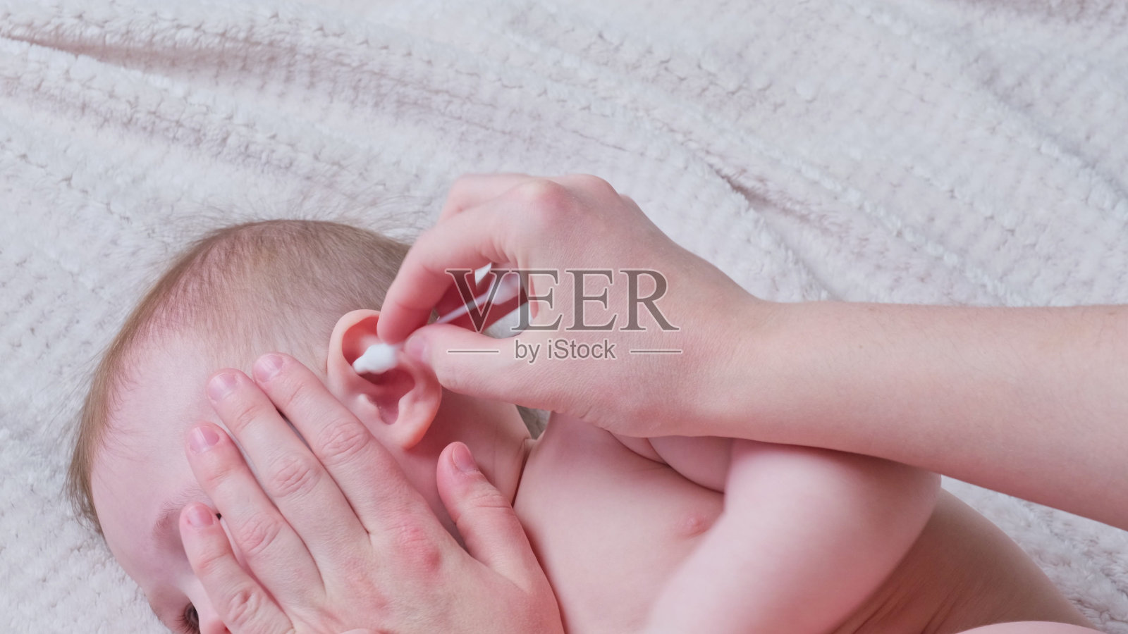 母亲用棉签清洁男婴耳朵照片摄影图片