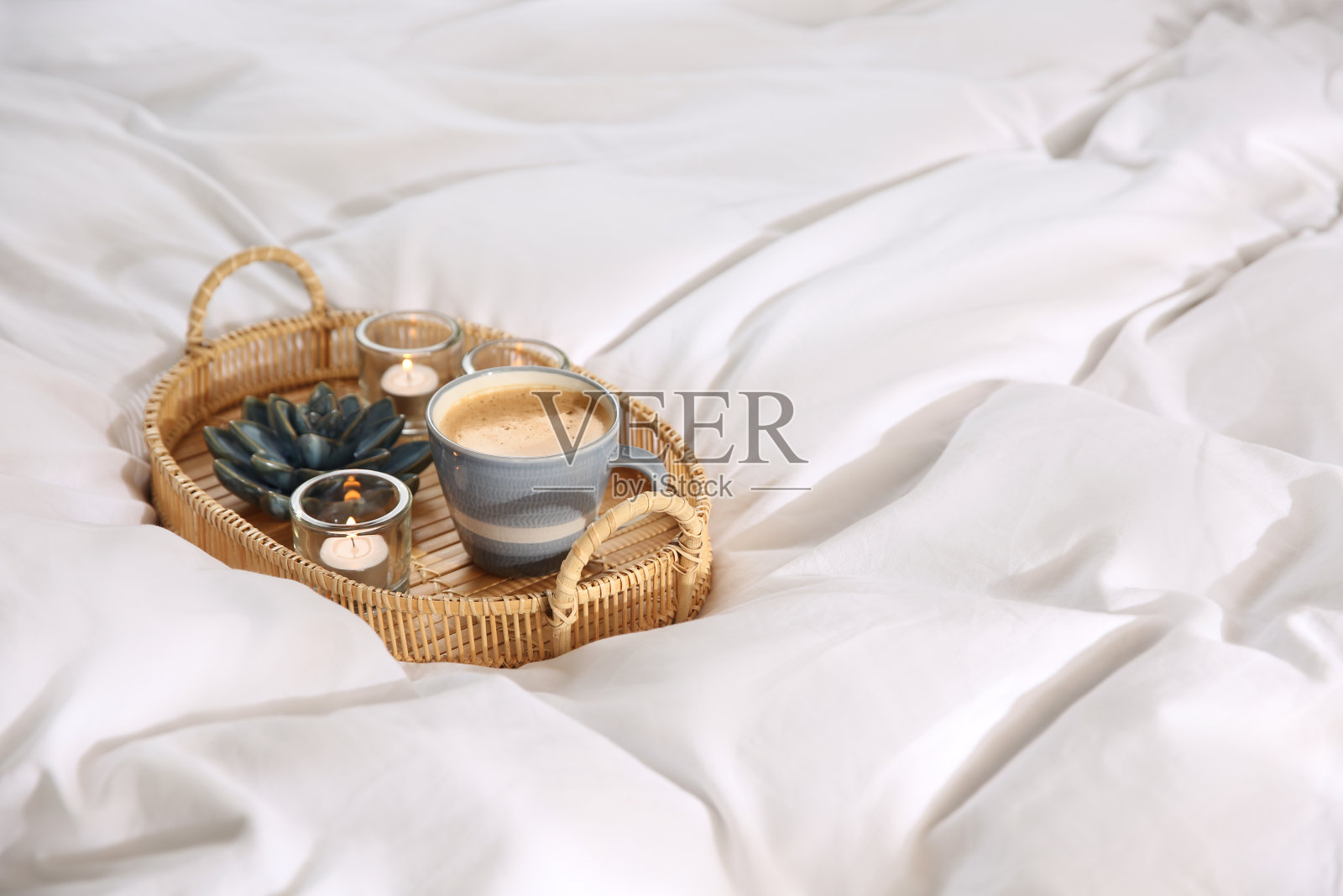 柳条托盘，咖啡杯，蜡烛放在柔软的白色毯子上照片摄影图片
