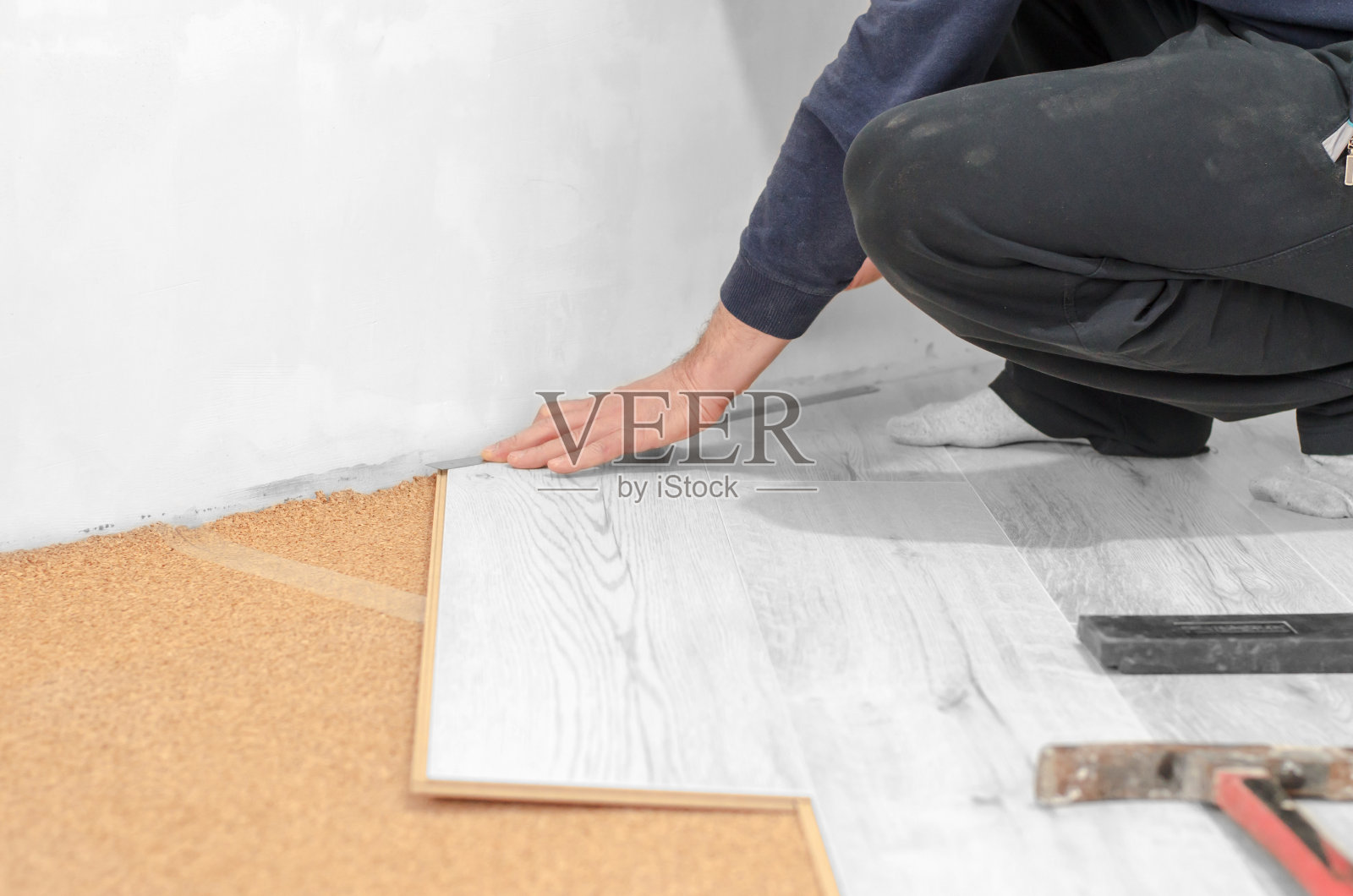 专业安装层压板。在公寓里修理。不认识的人正在铺设强化地板。照片摄影图片