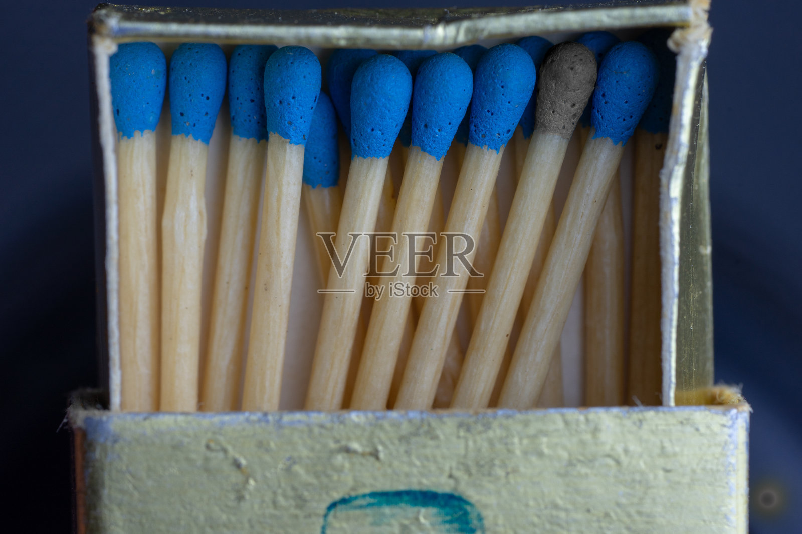 火柴盒里装满了蓝色头的火柴，只有一根突出显示是灰色头的火柴照片摄影图片
