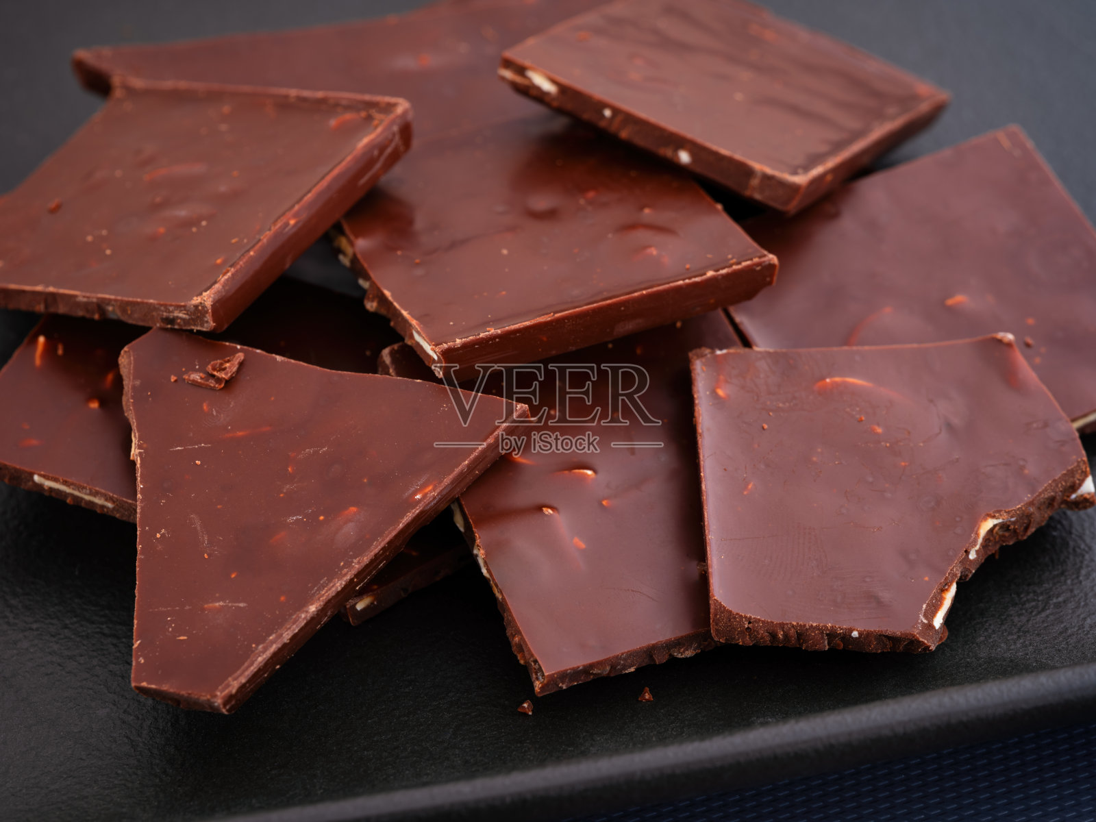 黑盘子上的碎巧克力。照片摄影图片