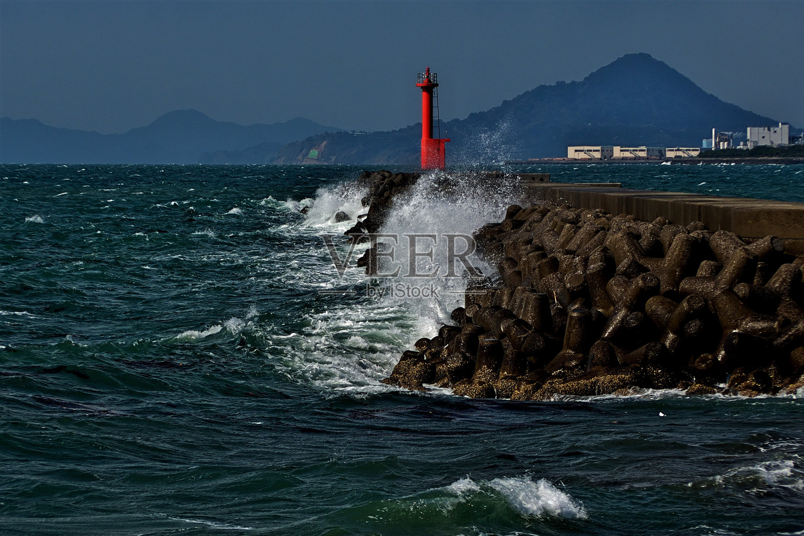 波涛汹涌，红色灯塔撞击防波堤照片摄影图片