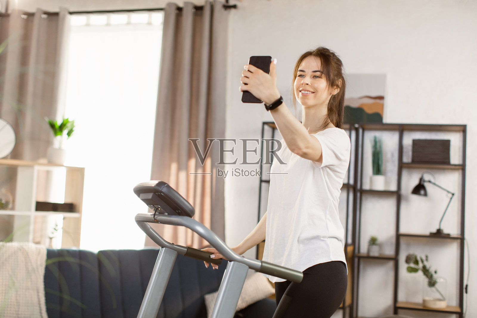 年轻女性做早操，在家打电话。照片摄影图片