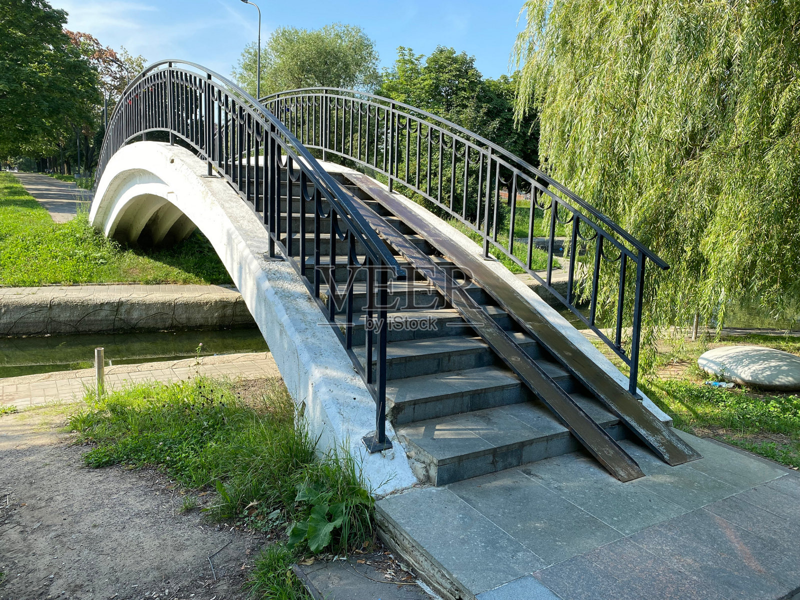 在干燥晴朗的夏日，公园池塘上的桥照片摄影图片