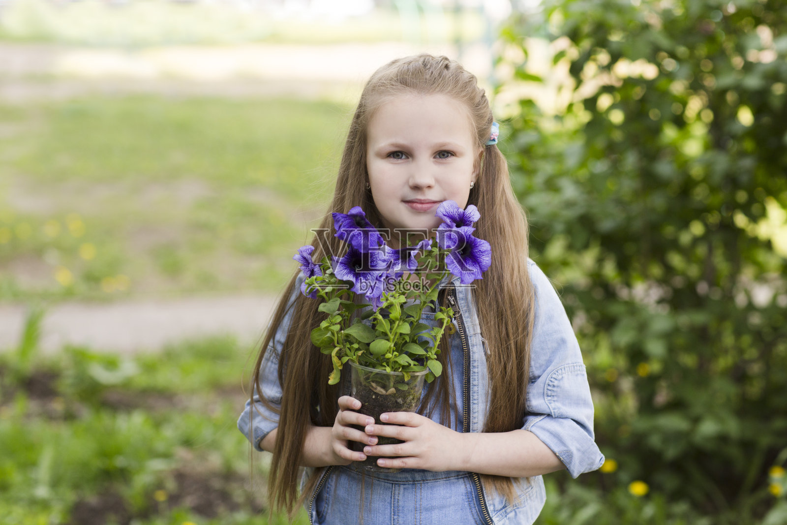春日，小女孩在家附近的花园里种花。孩子帮妈妈在花园里干活。节奏缓慢的生命。享受小事。照片摄影图片