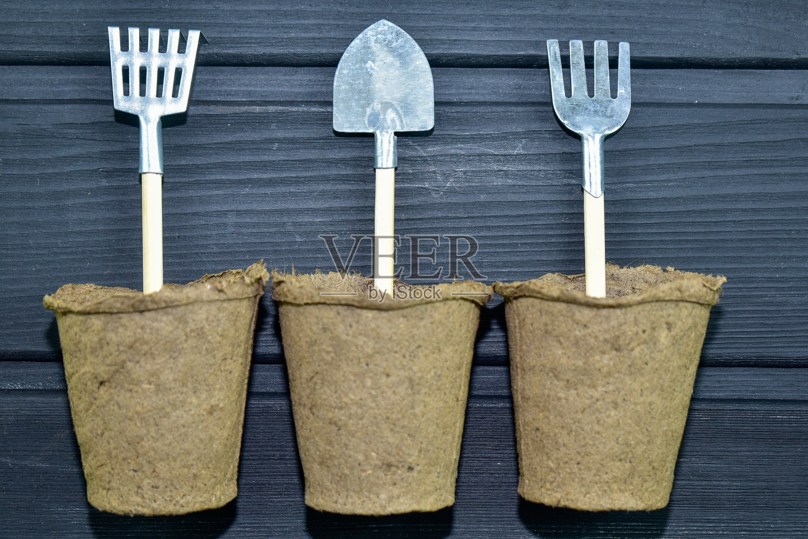黑色背景上的三个泥炭盆，里面有小的园艺工具。特写镜头。俯视图照片摄影图片