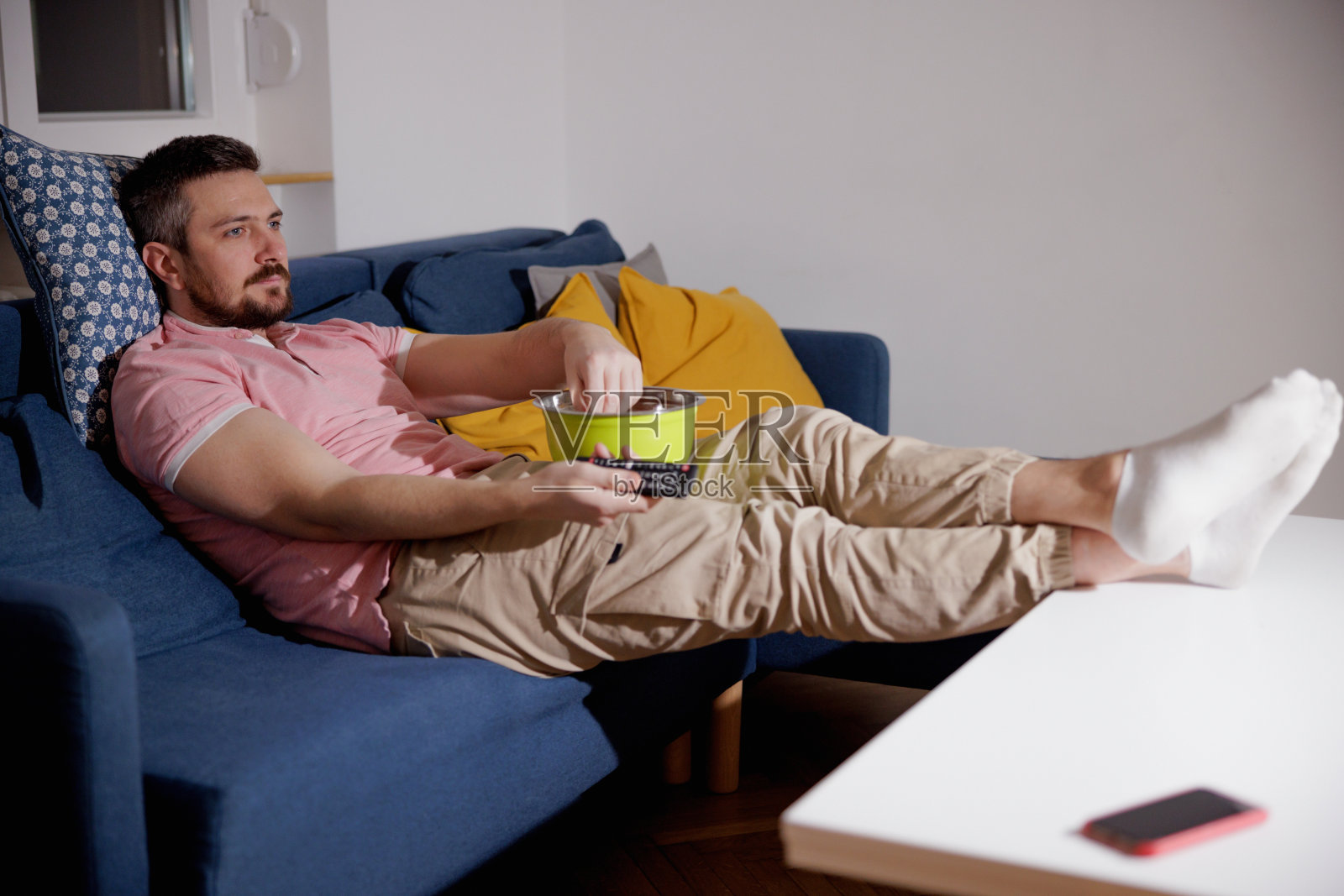 男人靠在沙发上，脚搁在咖啡桌上，换频道照片摄影图片