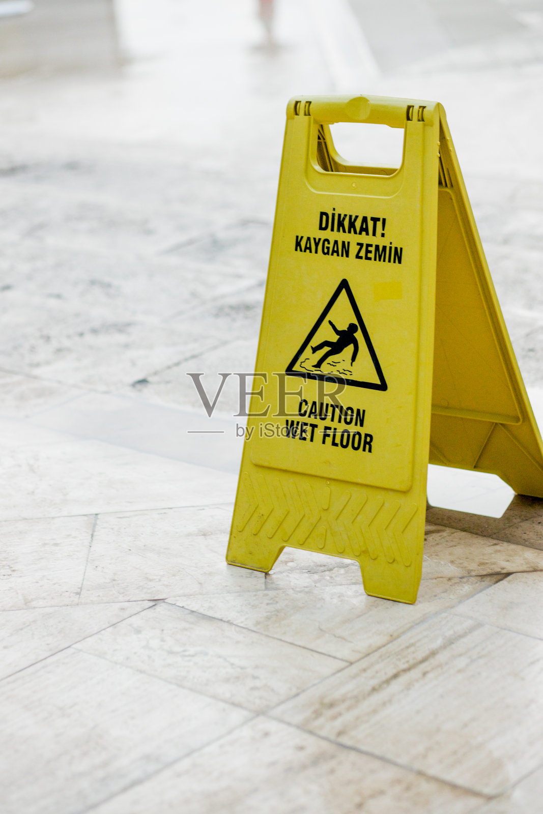 黄色标志警告地面湿滑，有摔倒在土耳其语和英语上的危险照片摄影图片