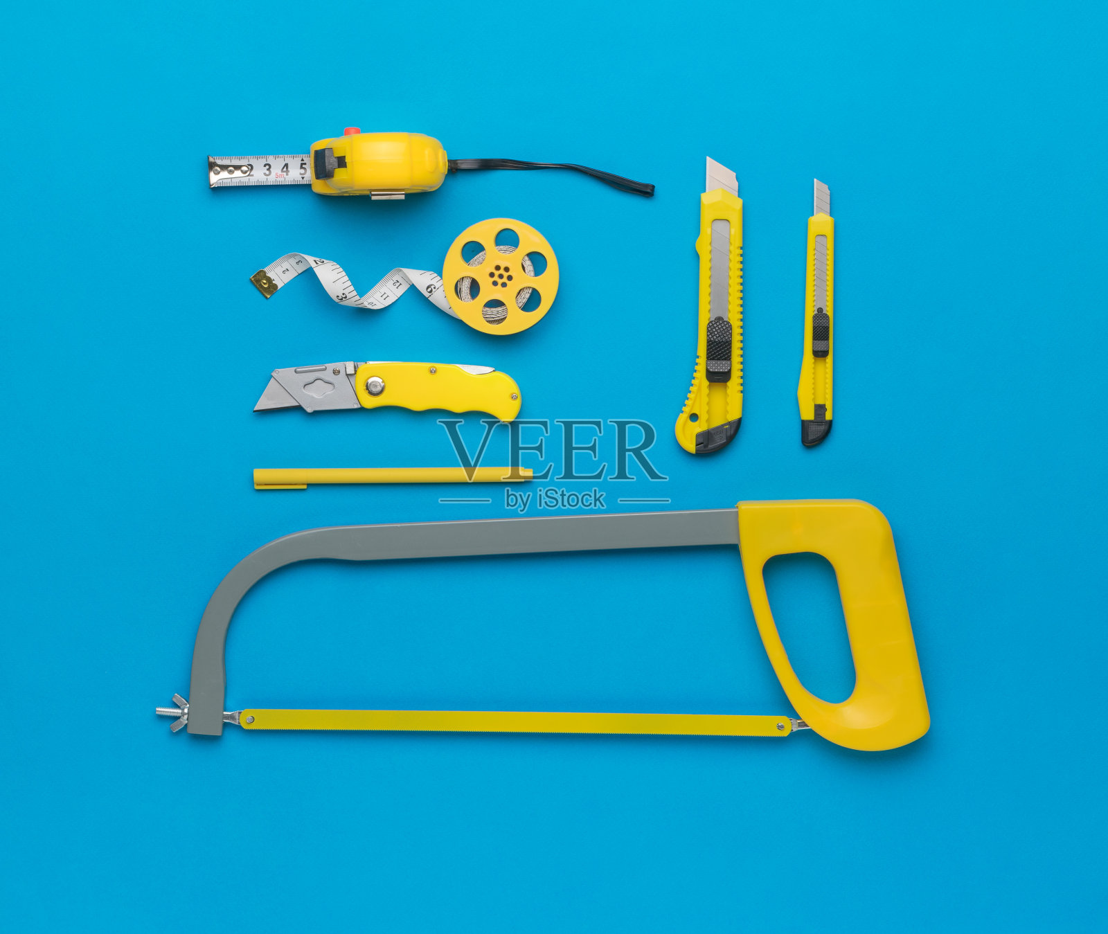 蓝色背景的刀具、手锯和卷尺。平的。照片摄影图片