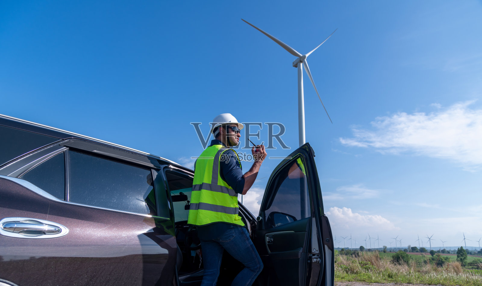 工程师穿着制服，戴着头盔持文件检查工作，在风电场旋转发电。绿色生态发电、风力发电、可持续能源理念。照片摄影图片