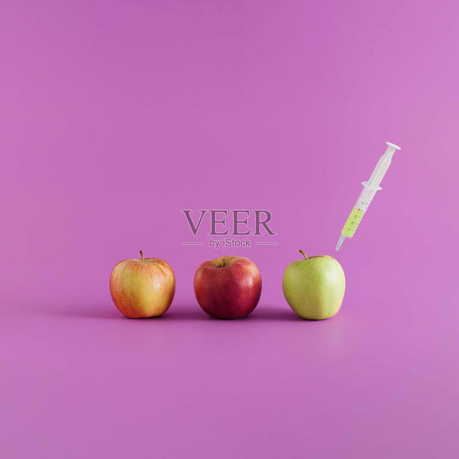 紫色背景上的三个苹果和一个注射器的最小视觉效果。医疗保健概念与复制空间。照片摄影图片