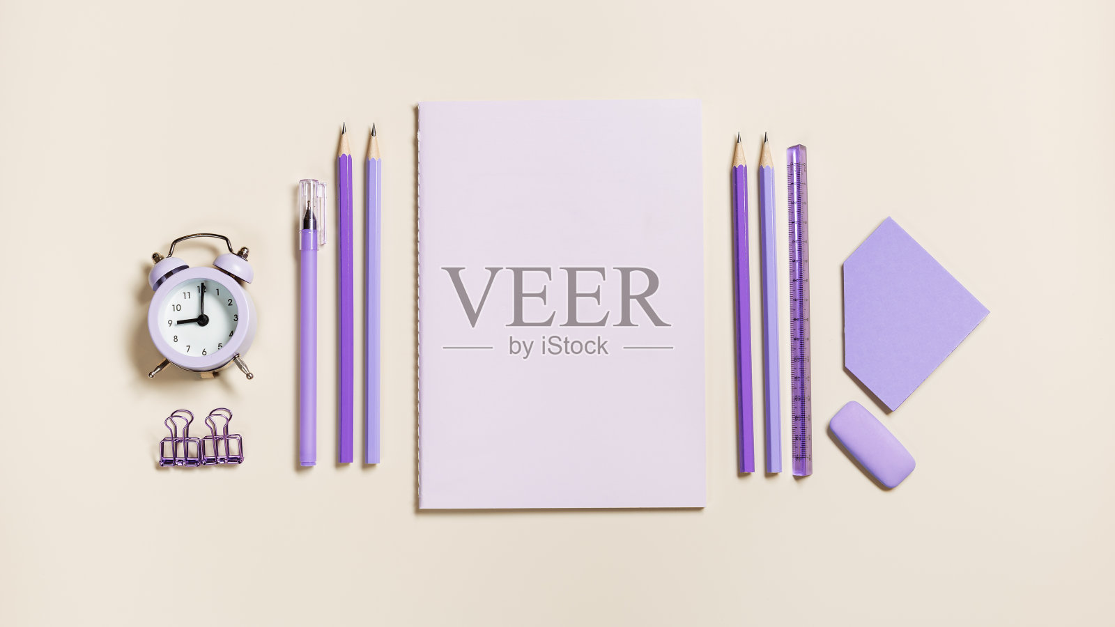 学校文具很接近潮流颜色，铅笔、钢笔、回形针、闹钟方块组成。回到学校，平坦地躺在米色的背景上。桌上摆放着柔和的办公用品照片摄影图片