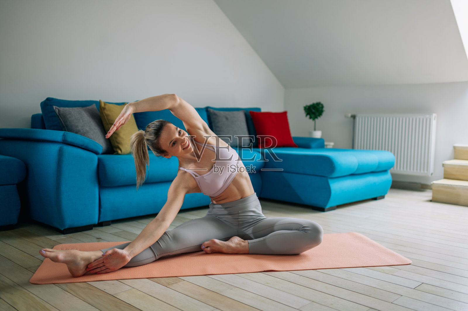 女人在家训练，坐在健身垫上伸展腿照片摄影图片