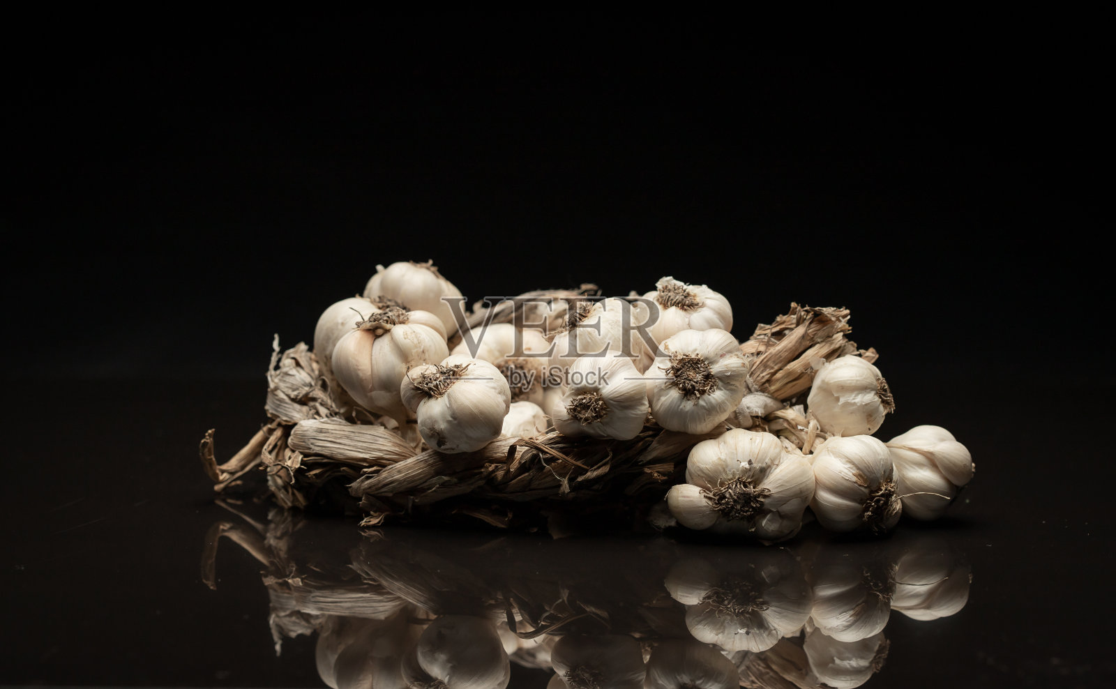芬芳的大蒜花环躺在黑暗的背景上。农业和农业照片摄影图片