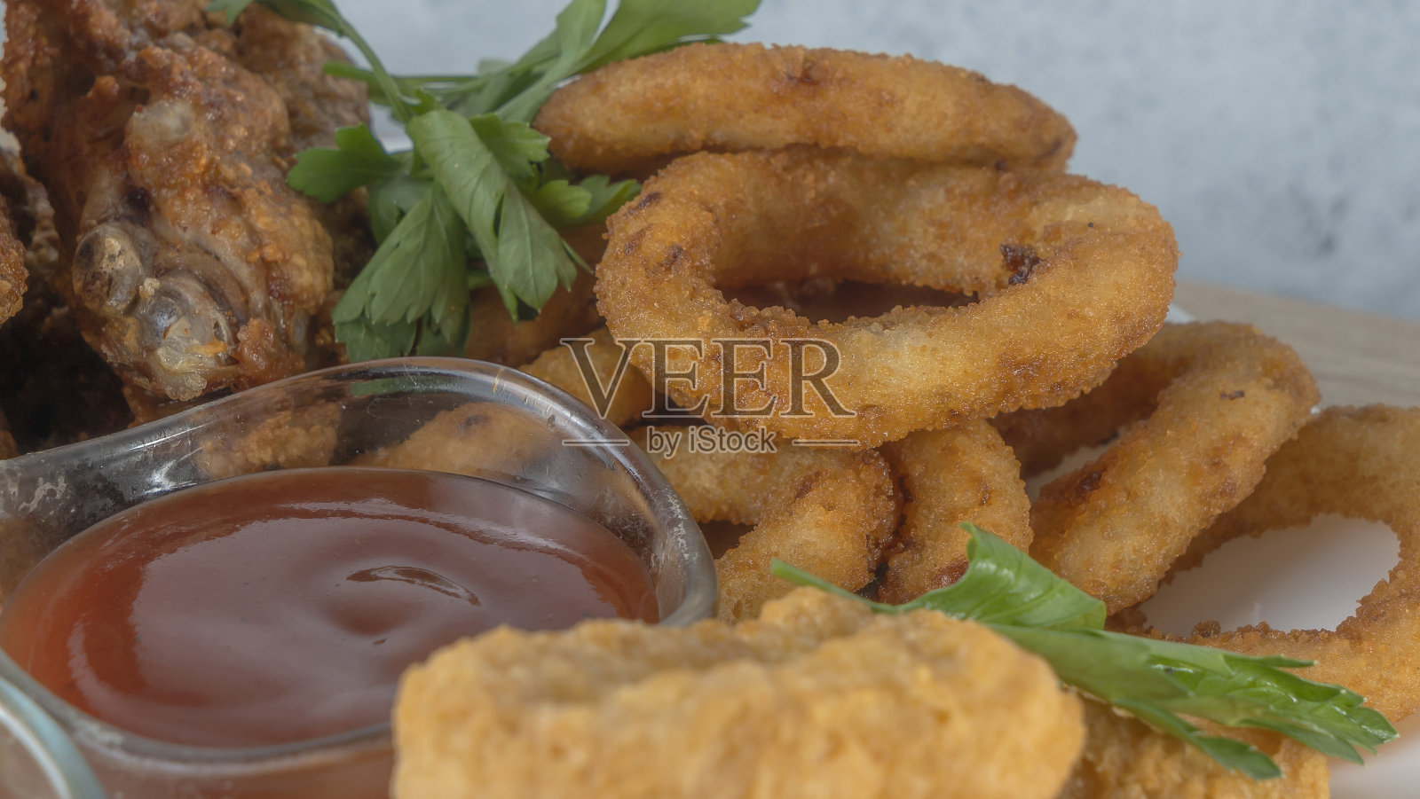 吧台的开胃菜。开胃菜配啤酒。烧烤鸡翅，炸鱿鱼圈，烤奶酪和几种不同的酱料。照片摄影图片