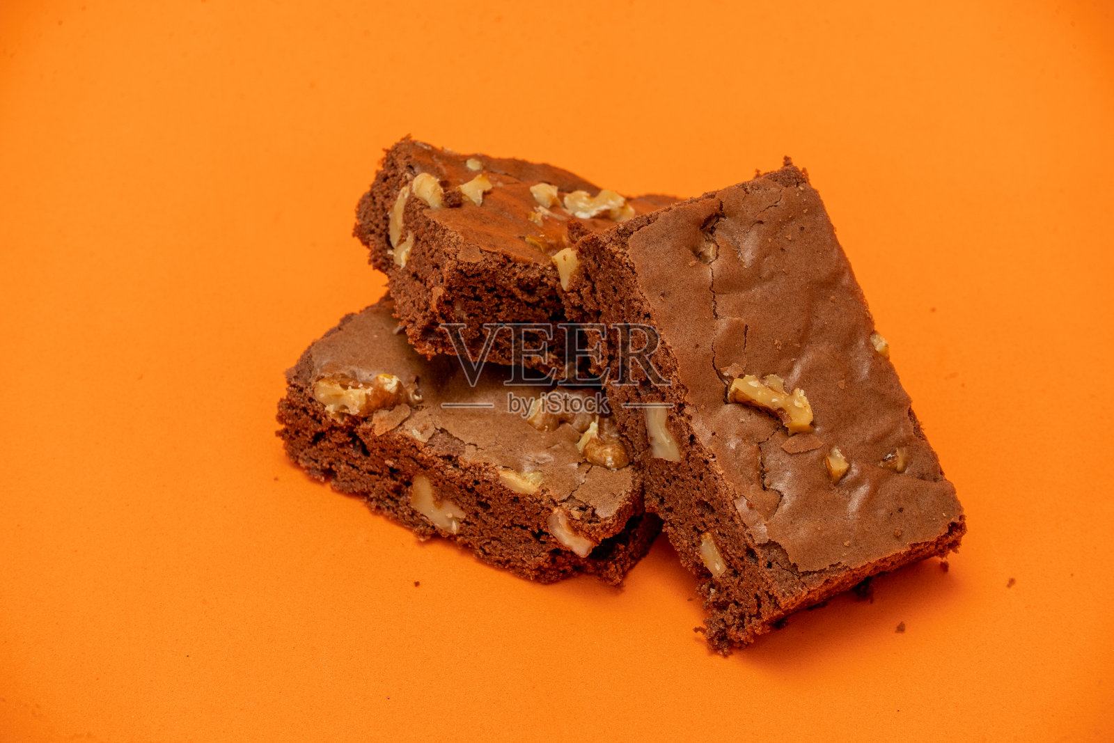 自制巧克力布朗尼蛋糕配核桃块。橙色背景。自然、健康的食品理念。照片摄影图片