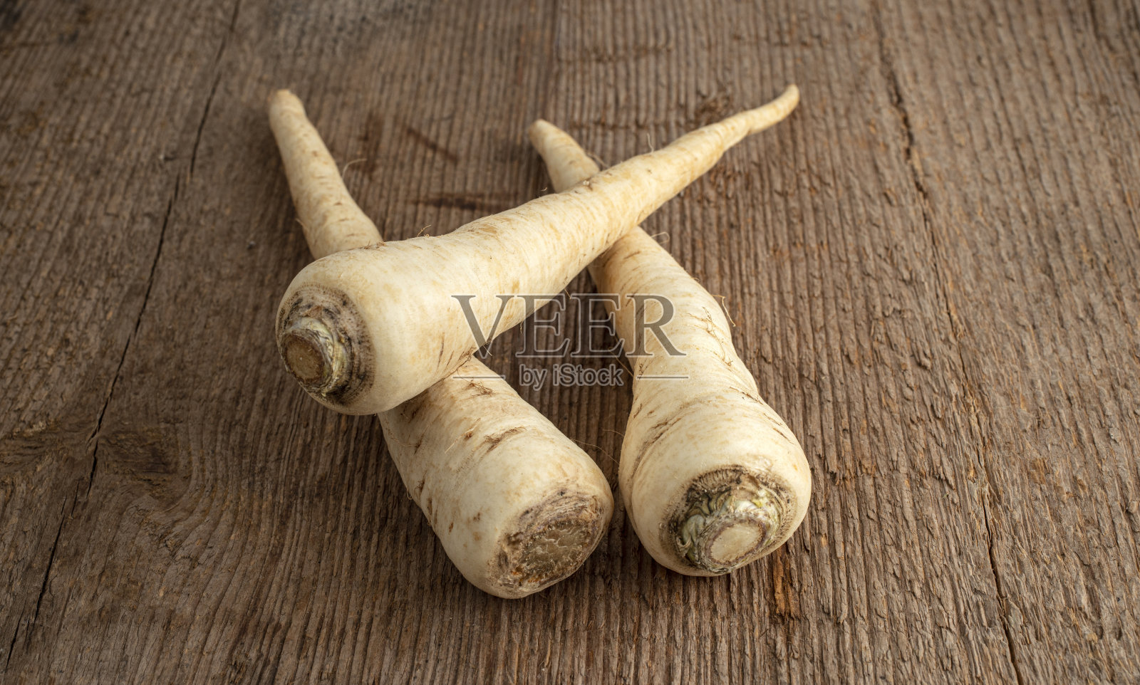 三根欧芹根躺在一张粗糙的木桌上照片摄影图片