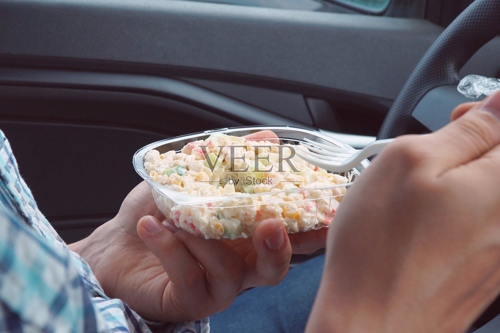 老兄，坐在车里，用一次性塑料盘子里的蛋黄酱吃沙拉照片摄影图片