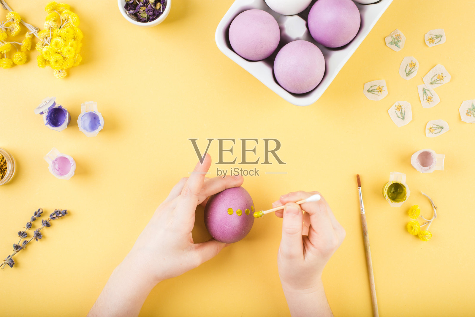 孩子的手在黄色的背景上装饰复活节彩蛋。复活节快乐概念照片摄影图片