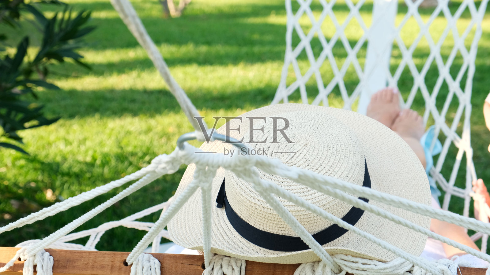 戴草帽的女性在棕榈树旁的吊床上休息，享受着宁静和放松。假期的概念照片摄影图片