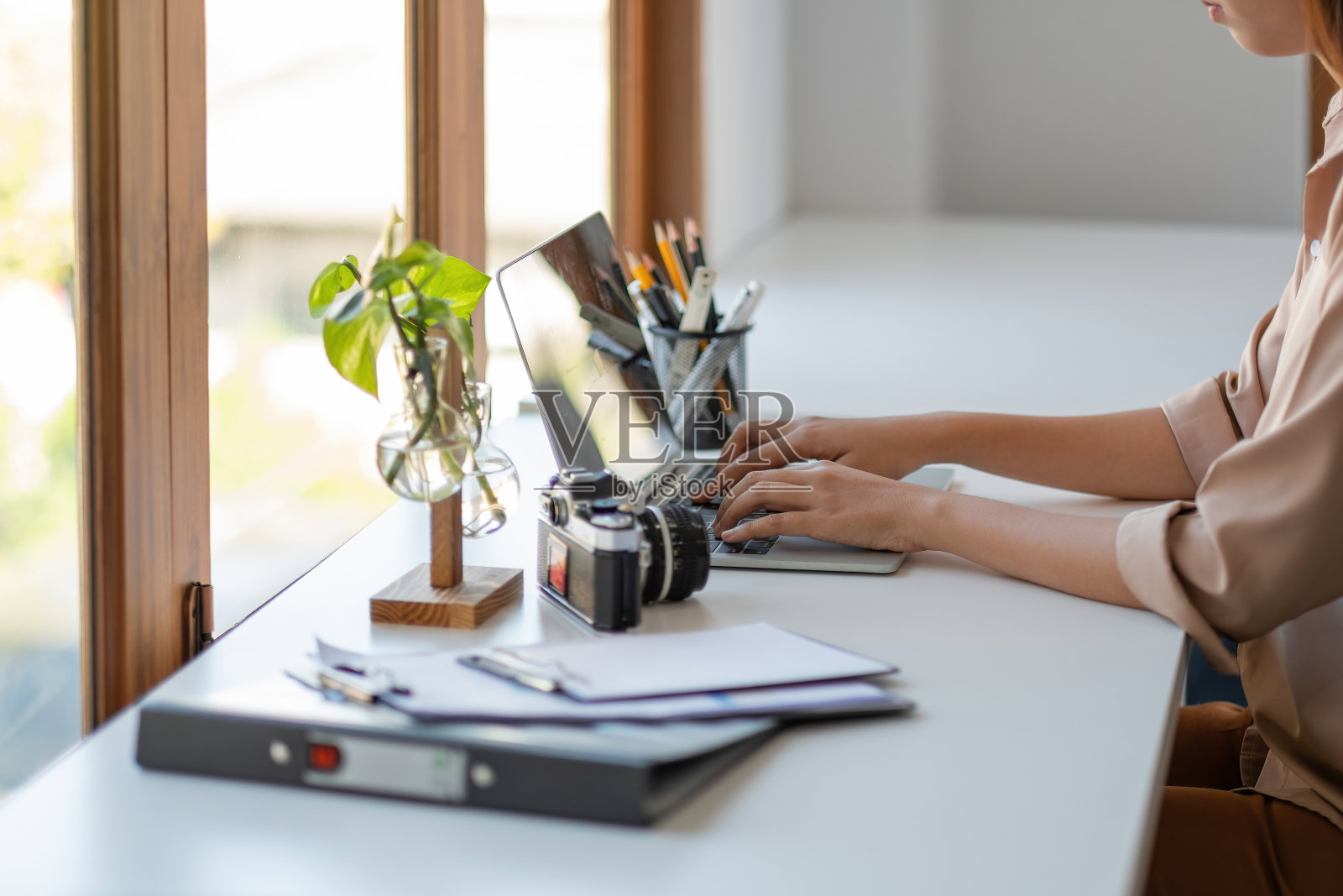 年轻的自由职业女性在现代的办公室里用笔记本电脑打字照片摄影图片