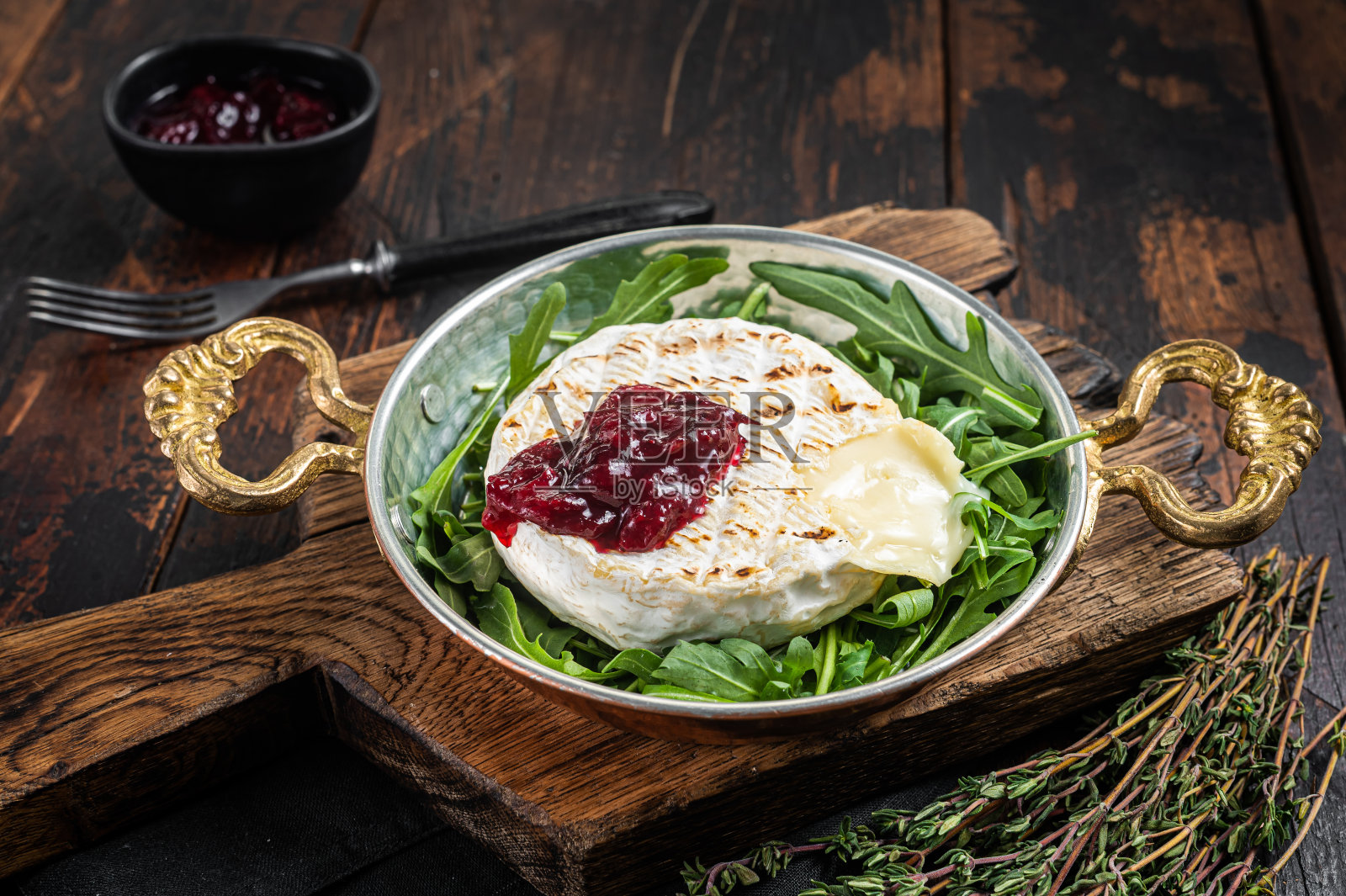 烤卡芒贝尔乳酪配蔓越莓酱，配芝麻菜沙拉。木制背景。俯视图照片摄影图片