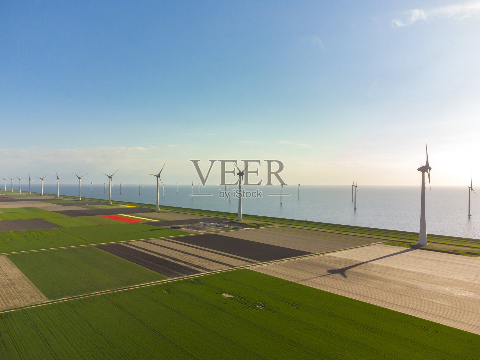 背景是农田和湖泊，堤防上的风力涡轮机。照片摄影图片