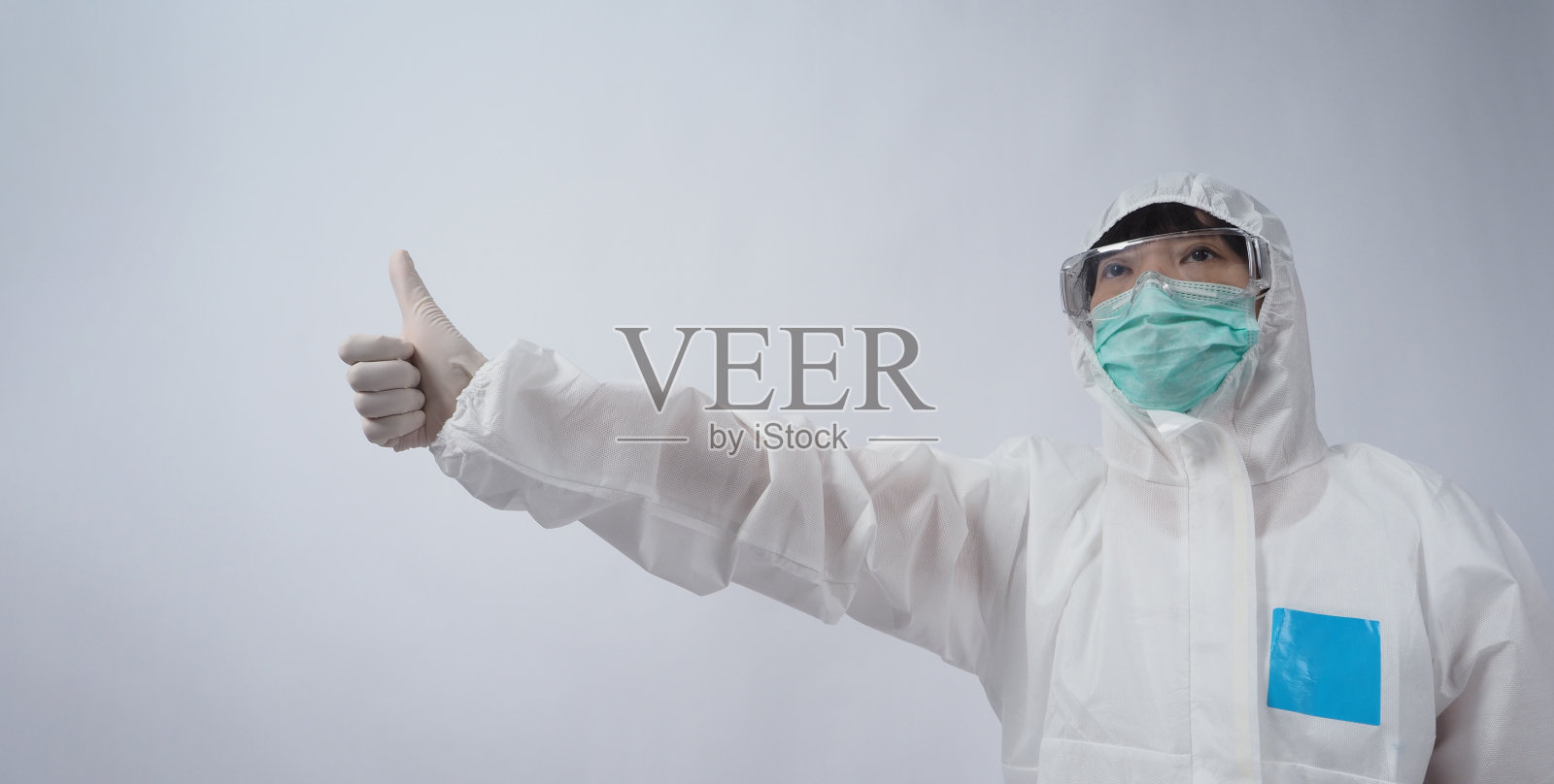 医生穿着个人防护服，戴着白色医用橡胶手套、透明护目镜和绿色N95口罩，以保护大流行的冠状病毒。手势做手势。代表战胜病毒的胜利。孤立。照片摄影图片