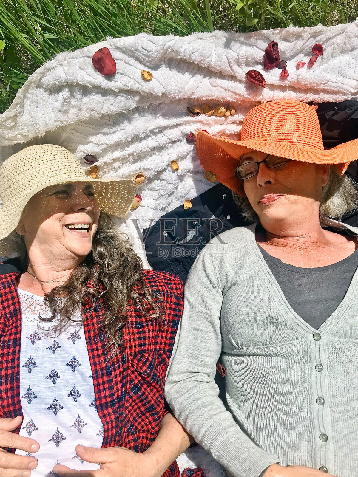 戴着草帽的姐姐们，在草地上嬉笑玩耍。照片摄影图片