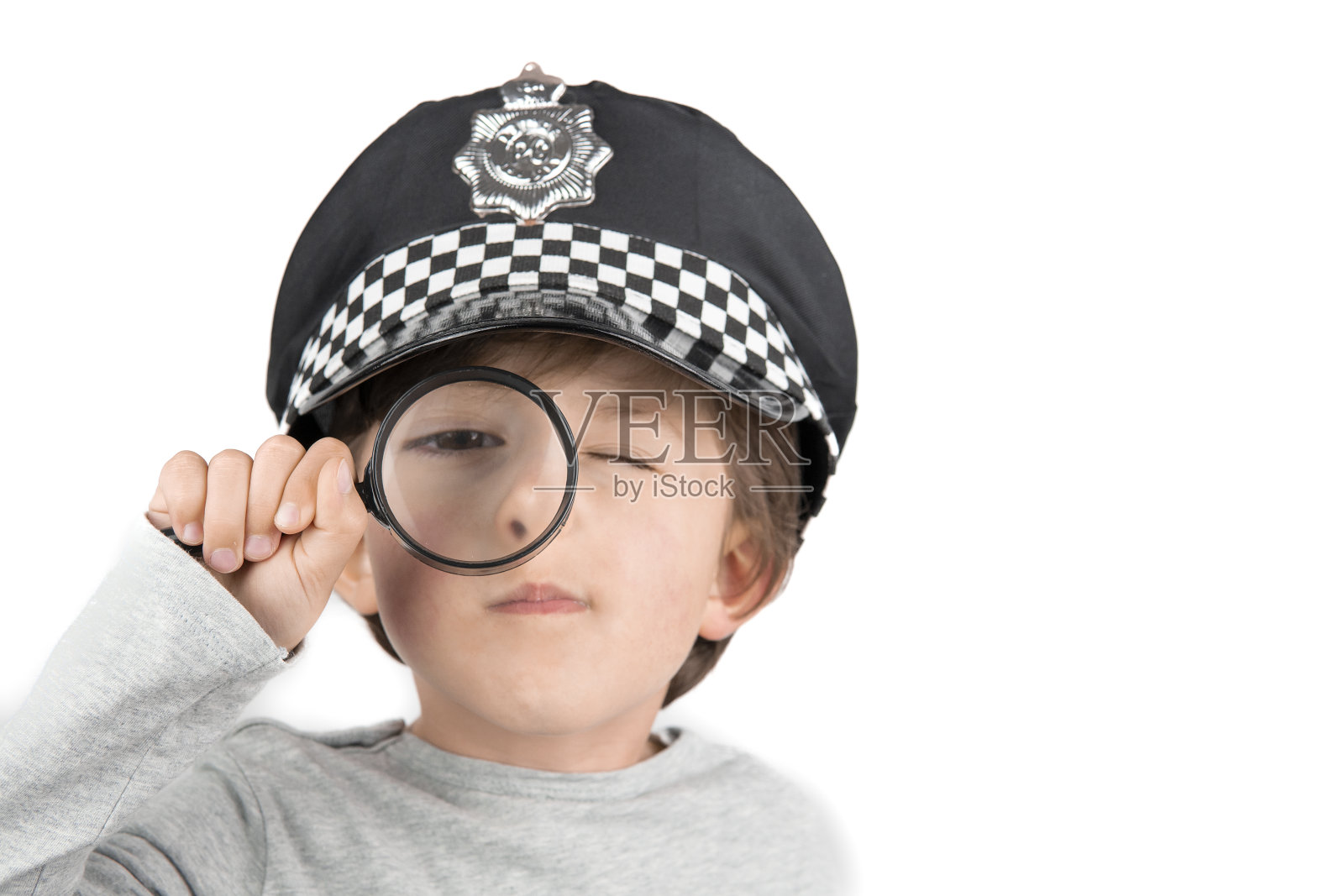 男孩拿着放大镜在白色的背景上。调查的概念照片摄影图片