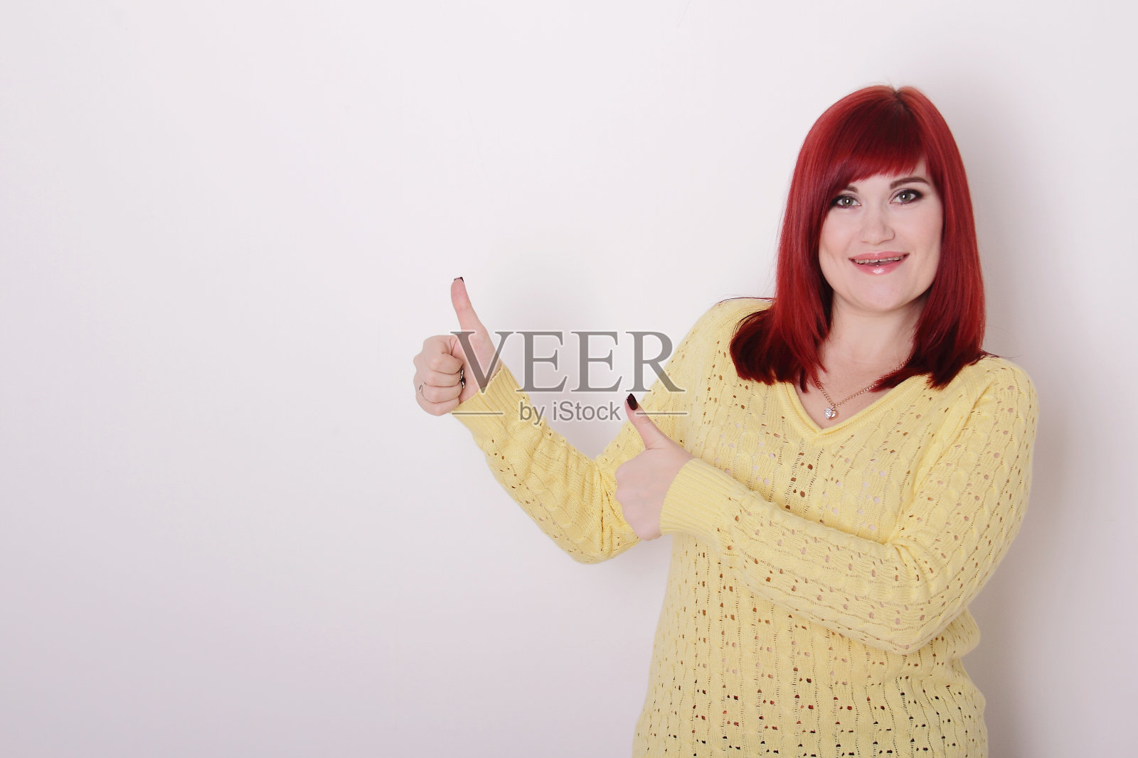 红发女人竖起手指，放文字的地方照片摄影图片