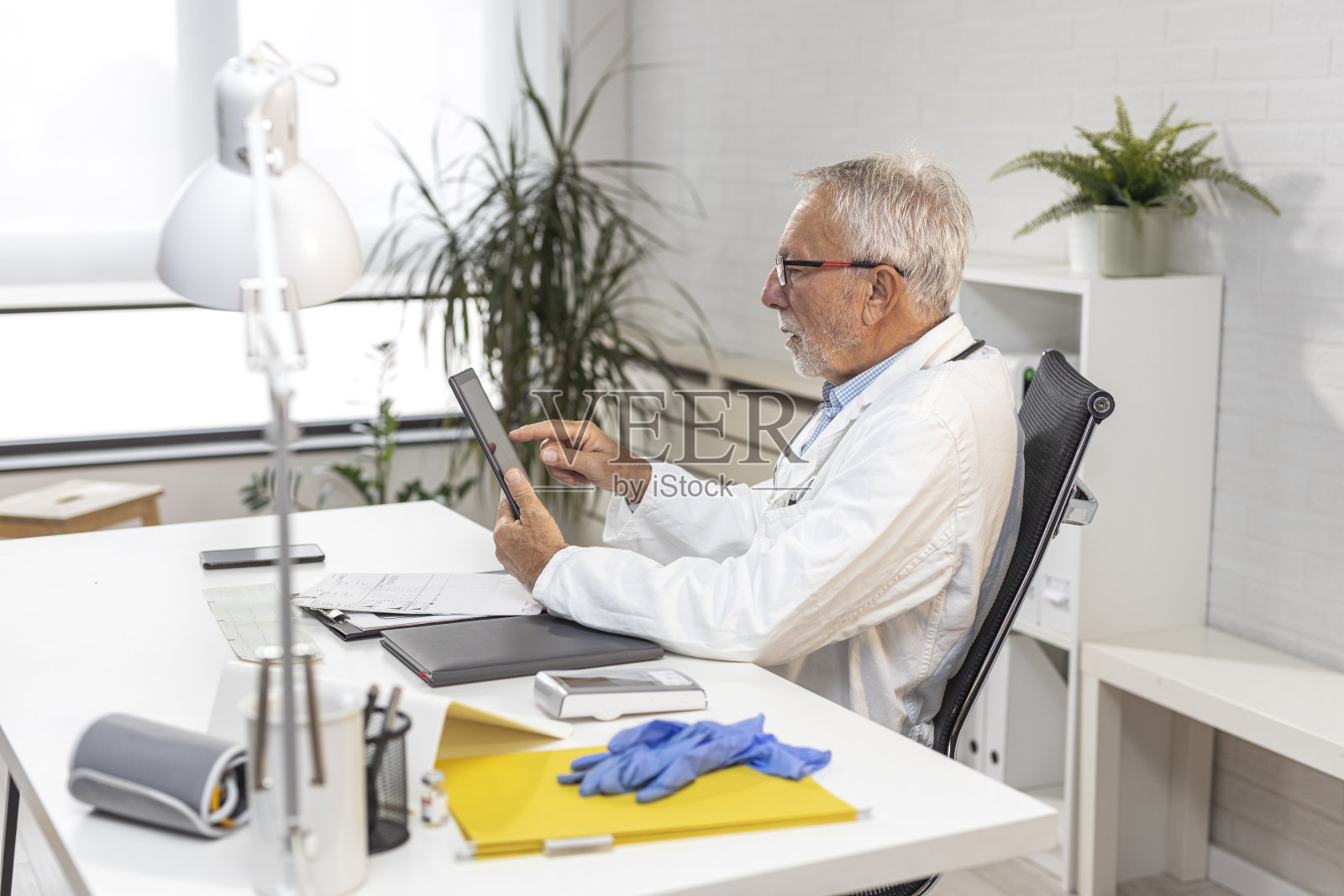 医生戴着眼镜坐在救护车里的办公室里的椅子上看着平板电脑照片摄影图片