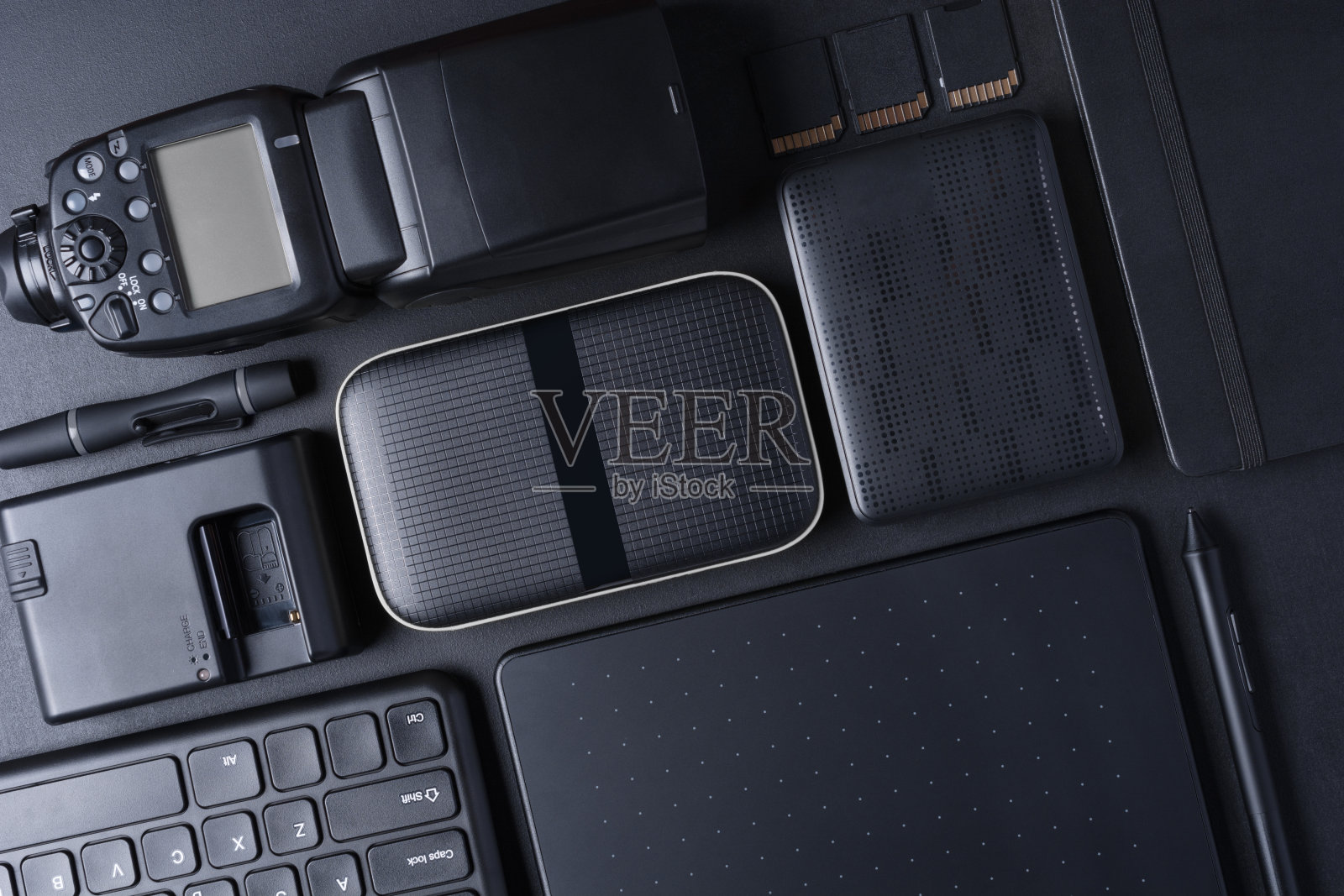 摄影师的工作空间配有数码相机、闪光灯、记忆卡、键盘和便携式硬盘照片摄影图片