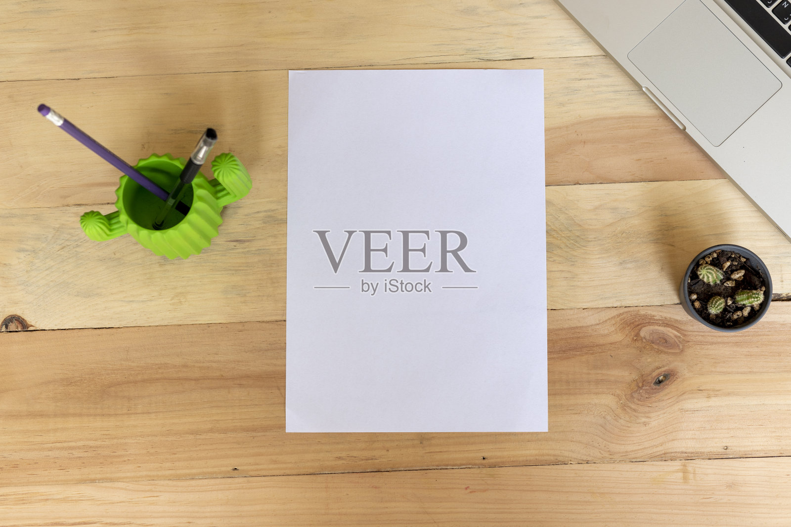 一张空白的A4纸放在一张木制的桌子上，上面放着办公用品照片摄影图片