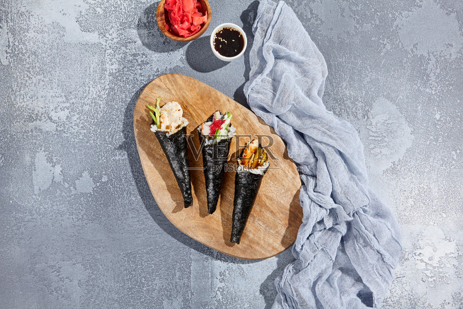 集temaki寿司在木盘在简约的风格。混凝土背景上的手工美学构图。现代日本料理——天麻寿司。照片摄影图片