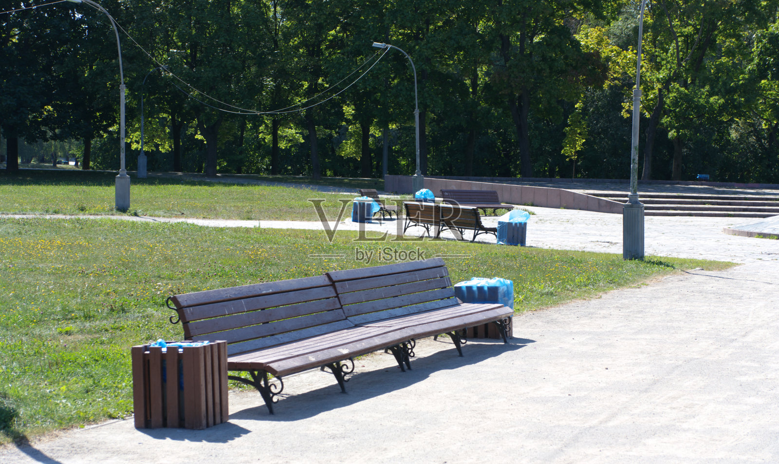 在干燥晴朗的夏日，公园里的长椅照片摄影图片