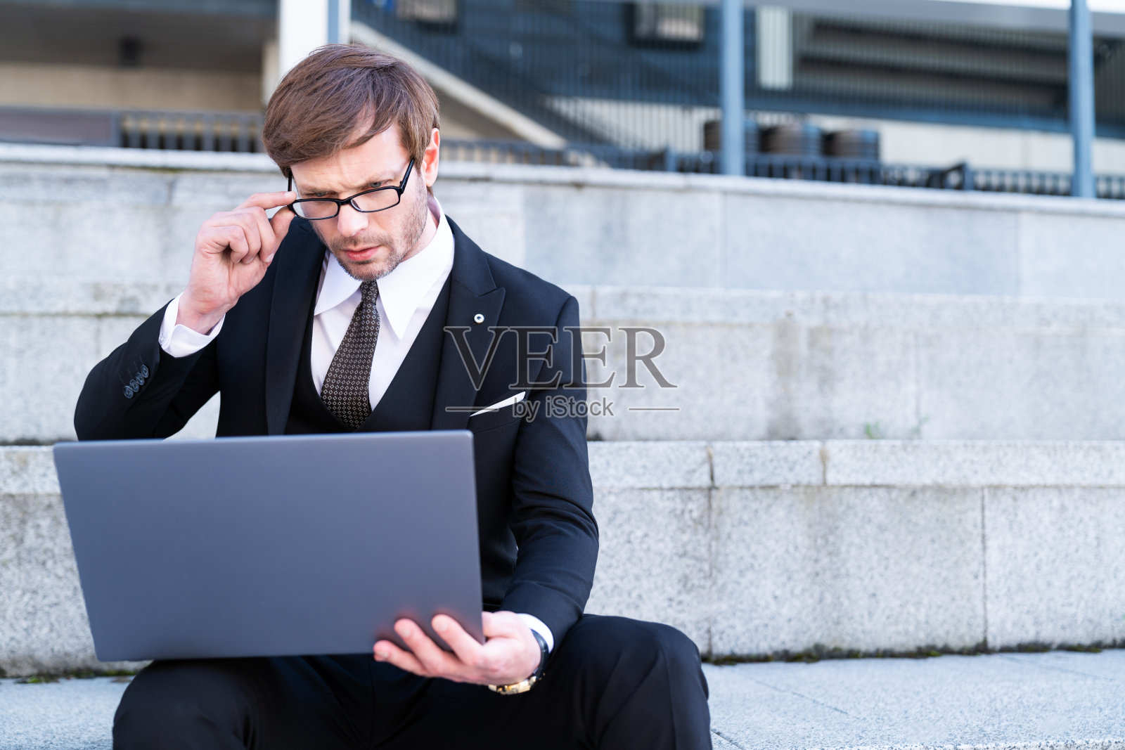 穿着正装的商人在户外使用笔记本电脑照片摄影图片