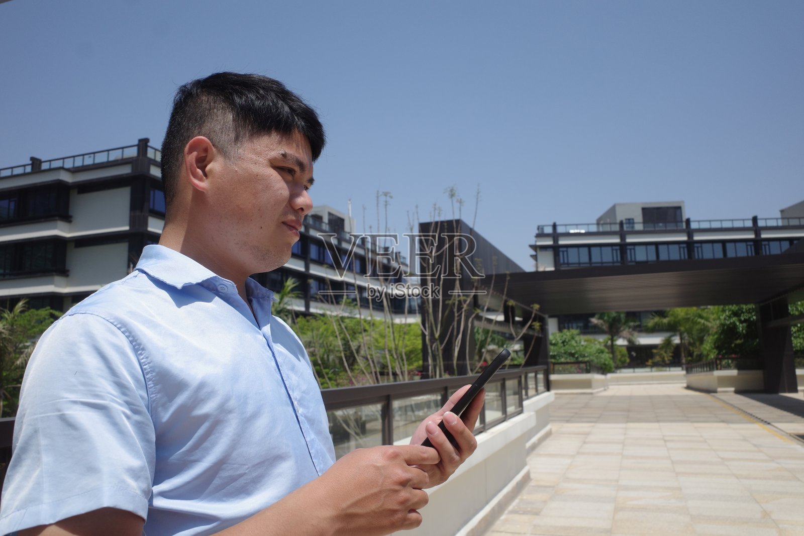 在办公大楼下面的人看着他的手机，想照片摄影图片