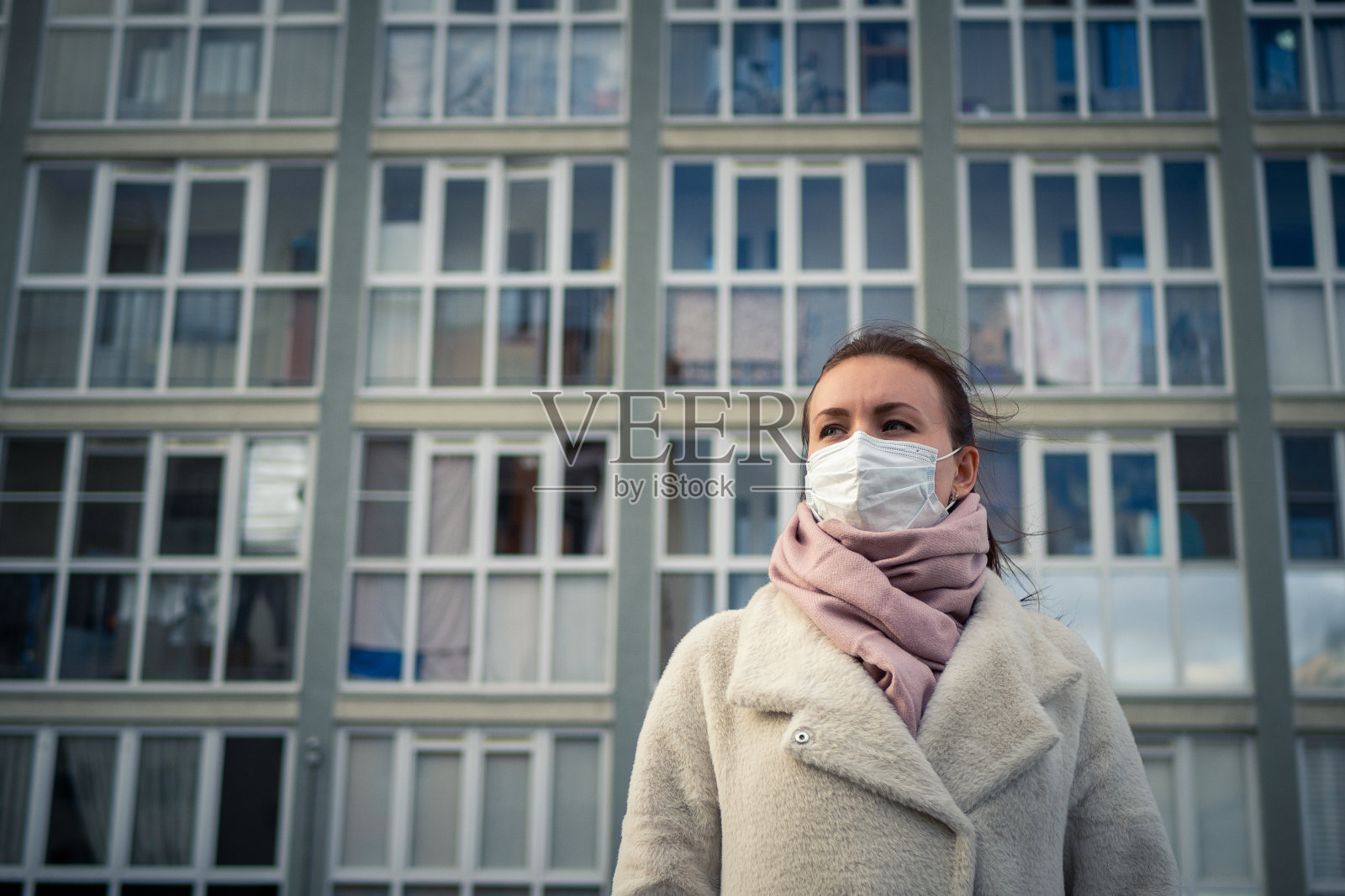 一个戴着面具的女孩在街上的照片。锁定Covid-19大流行。照片摄影图片