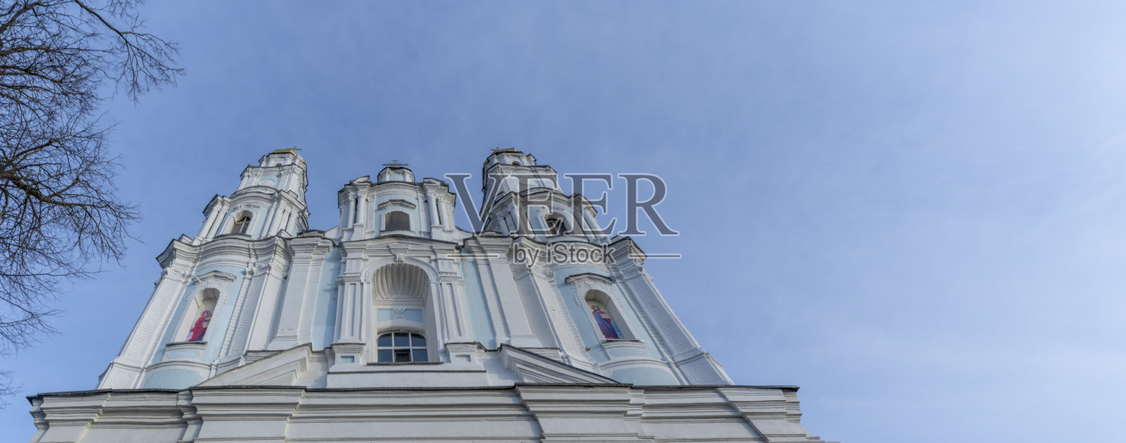 蓝色天空背景下的俄罗斯东正教教堂圆顶。在前景轮廓的光秃秃的树枝。崇拜和复活节。照片摄影图片