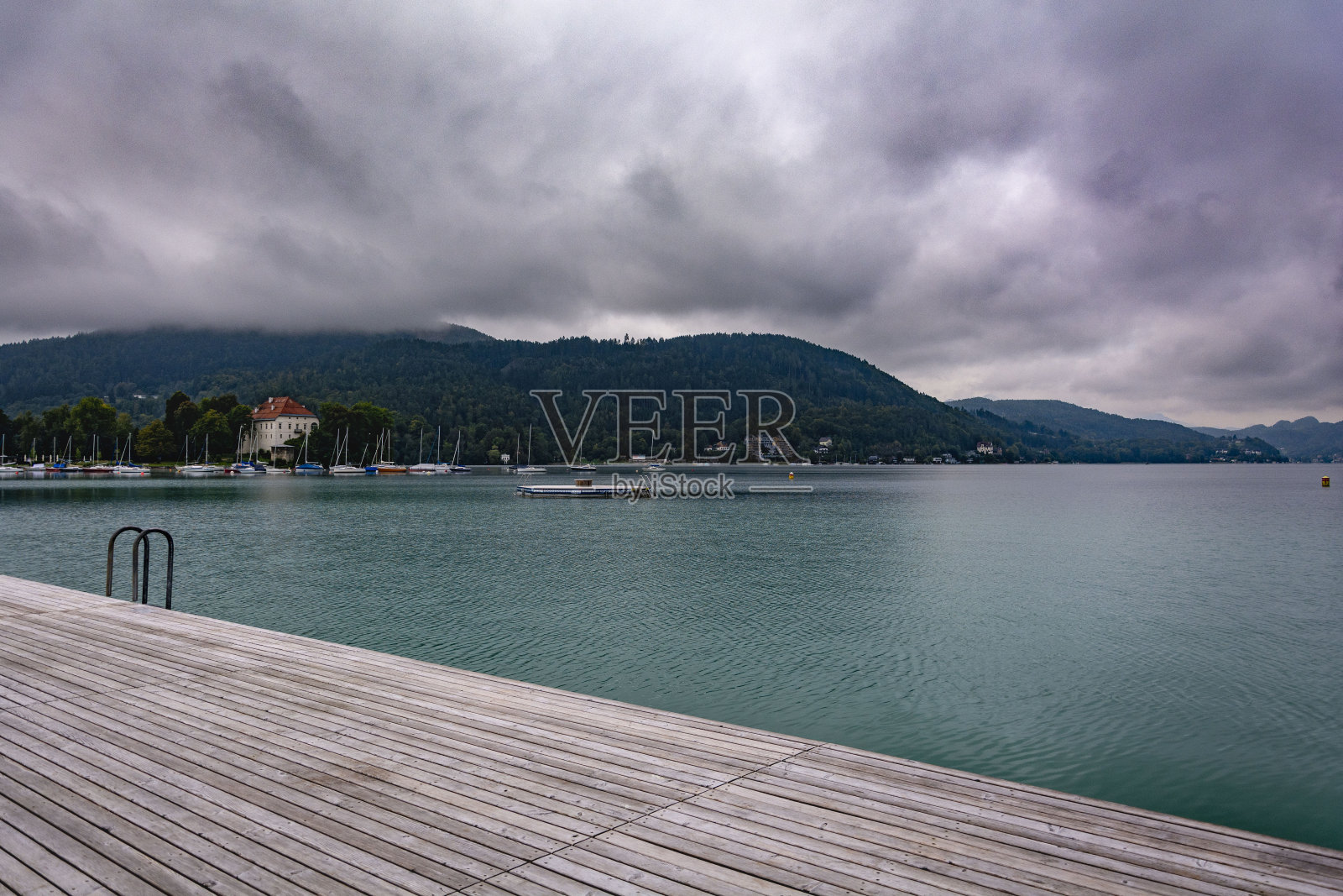 阴沉的多云宁静的早晨，在平静的湖水旁的湖木墩上照片摄影图片
