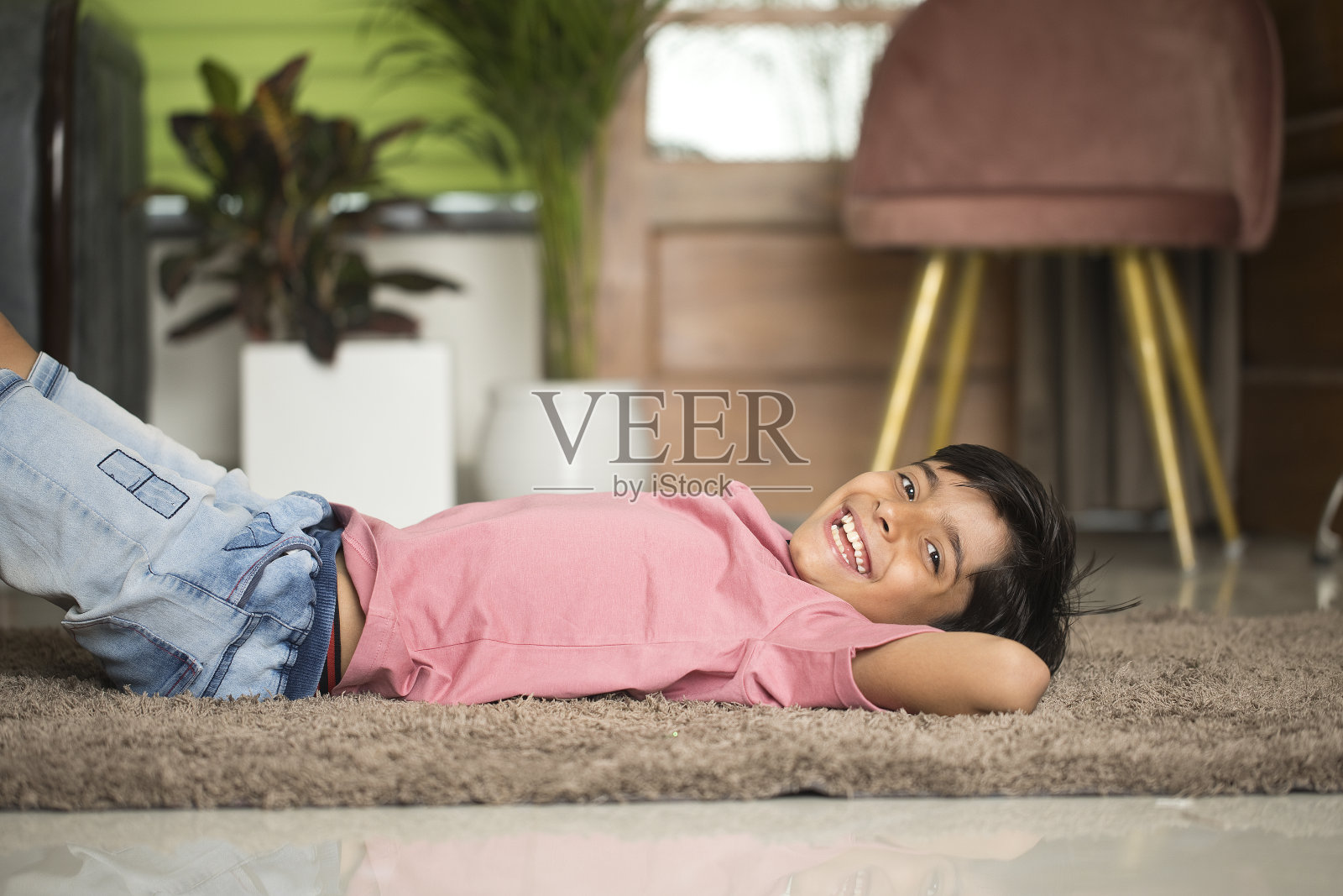 快乐的男孩躺在家里的地板上照片摄影图片